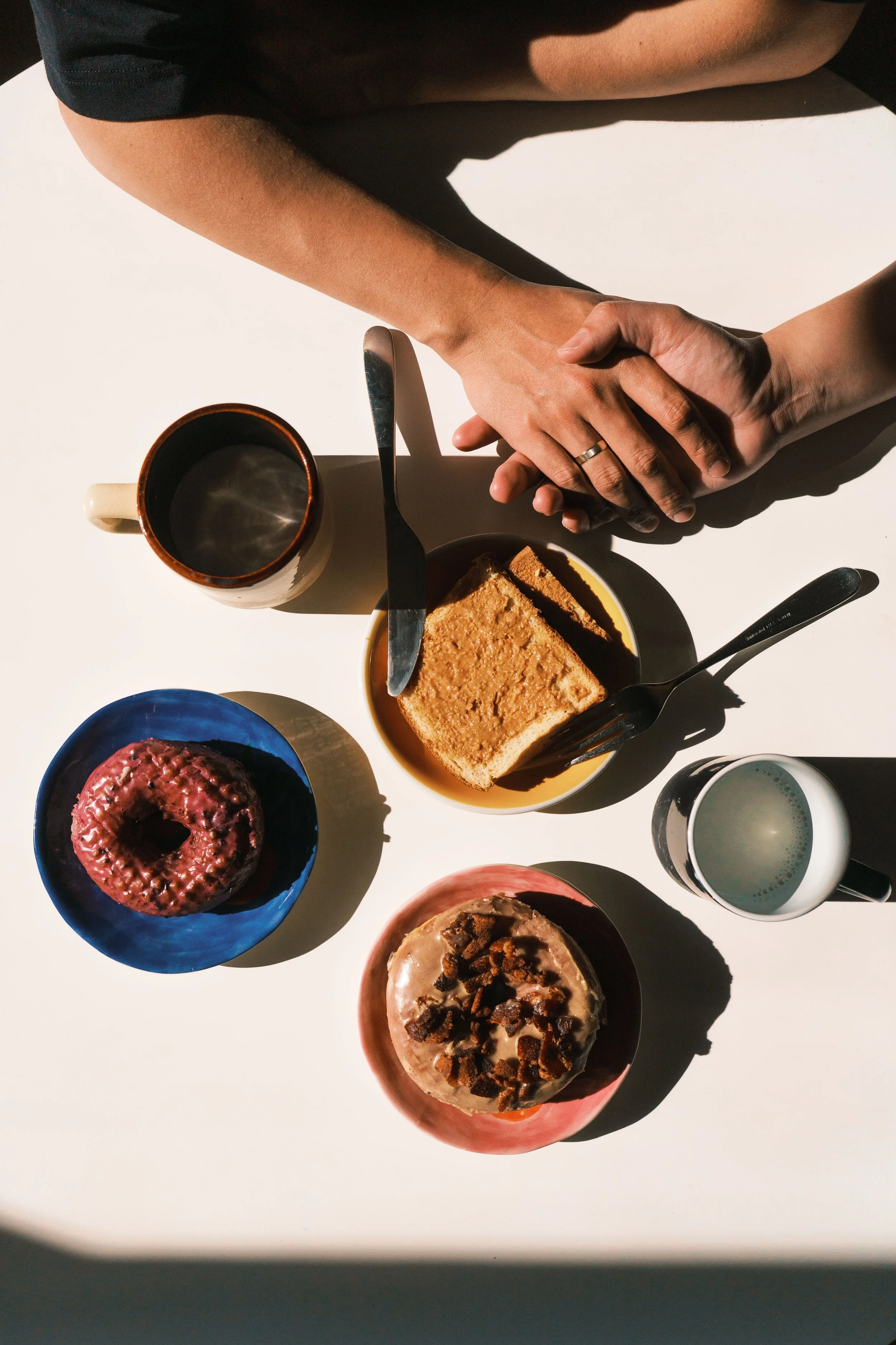 Top-down view of a table with various desserts, a cup of coffee, and two people shaking hands.