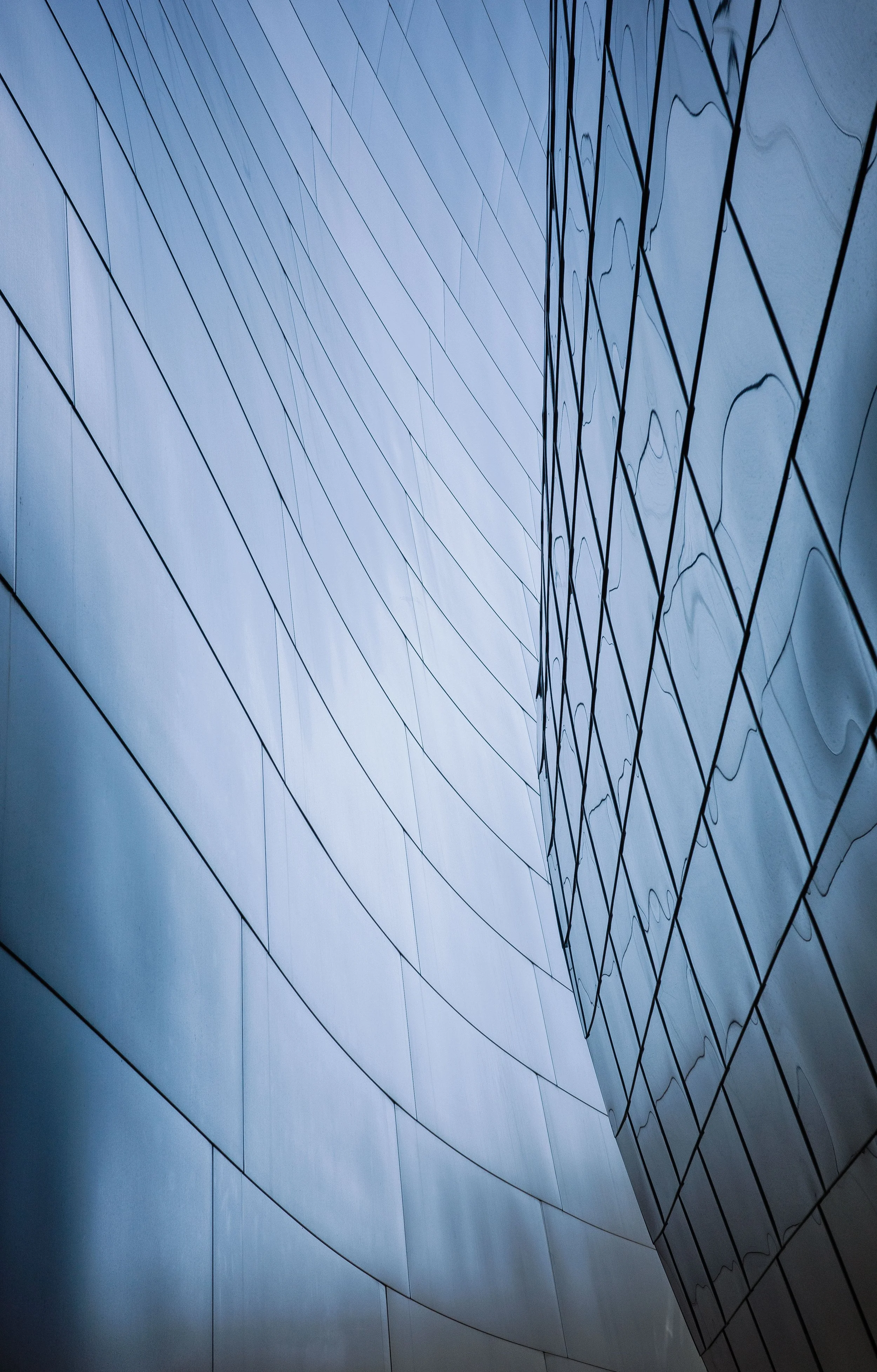 Close-up of a modern glass building with reflective surfaces and curved architectural lines.