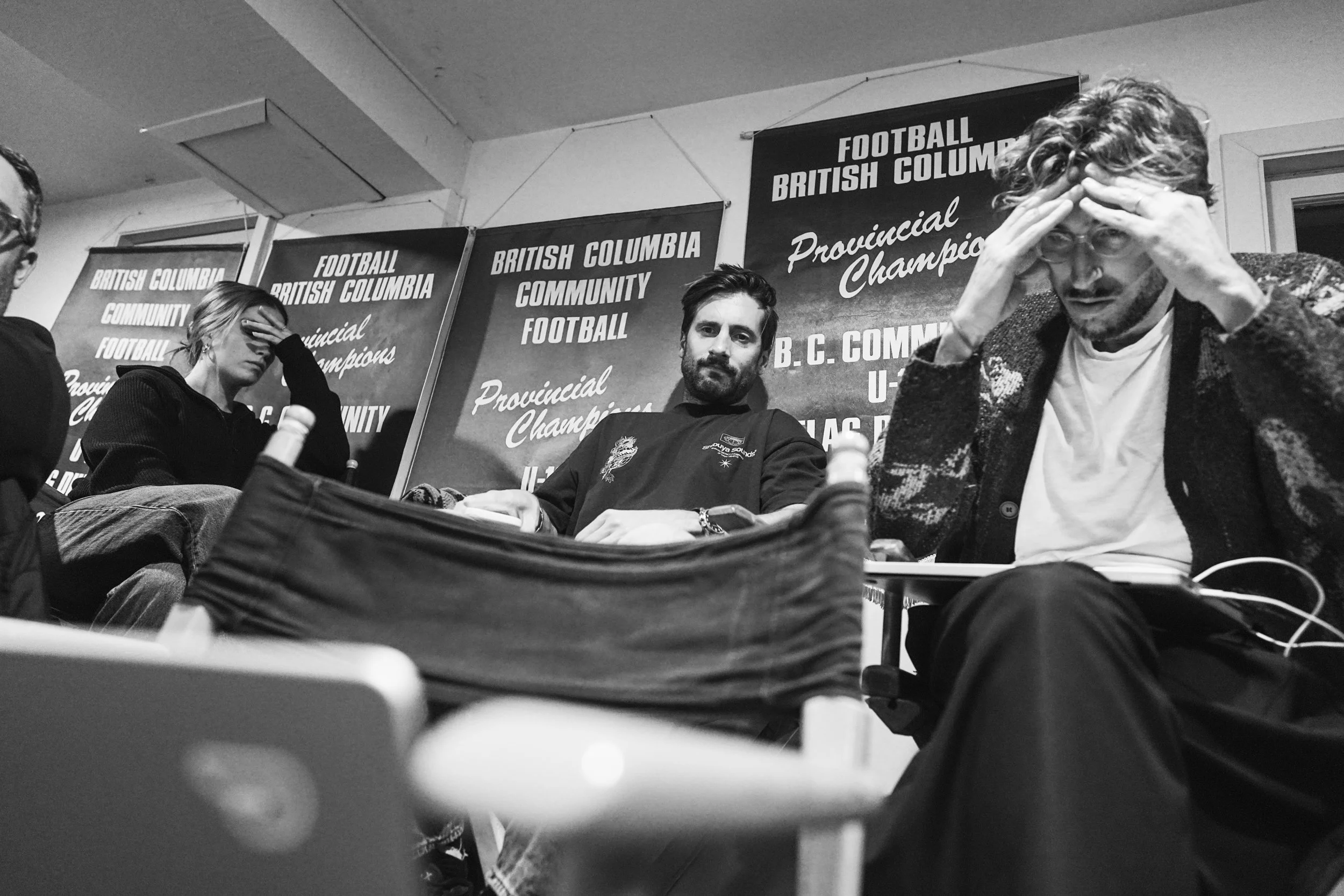 People sitting at a table during a meeting with banners in the background that read "British Columbia Community Football" and "Provincial Champions".