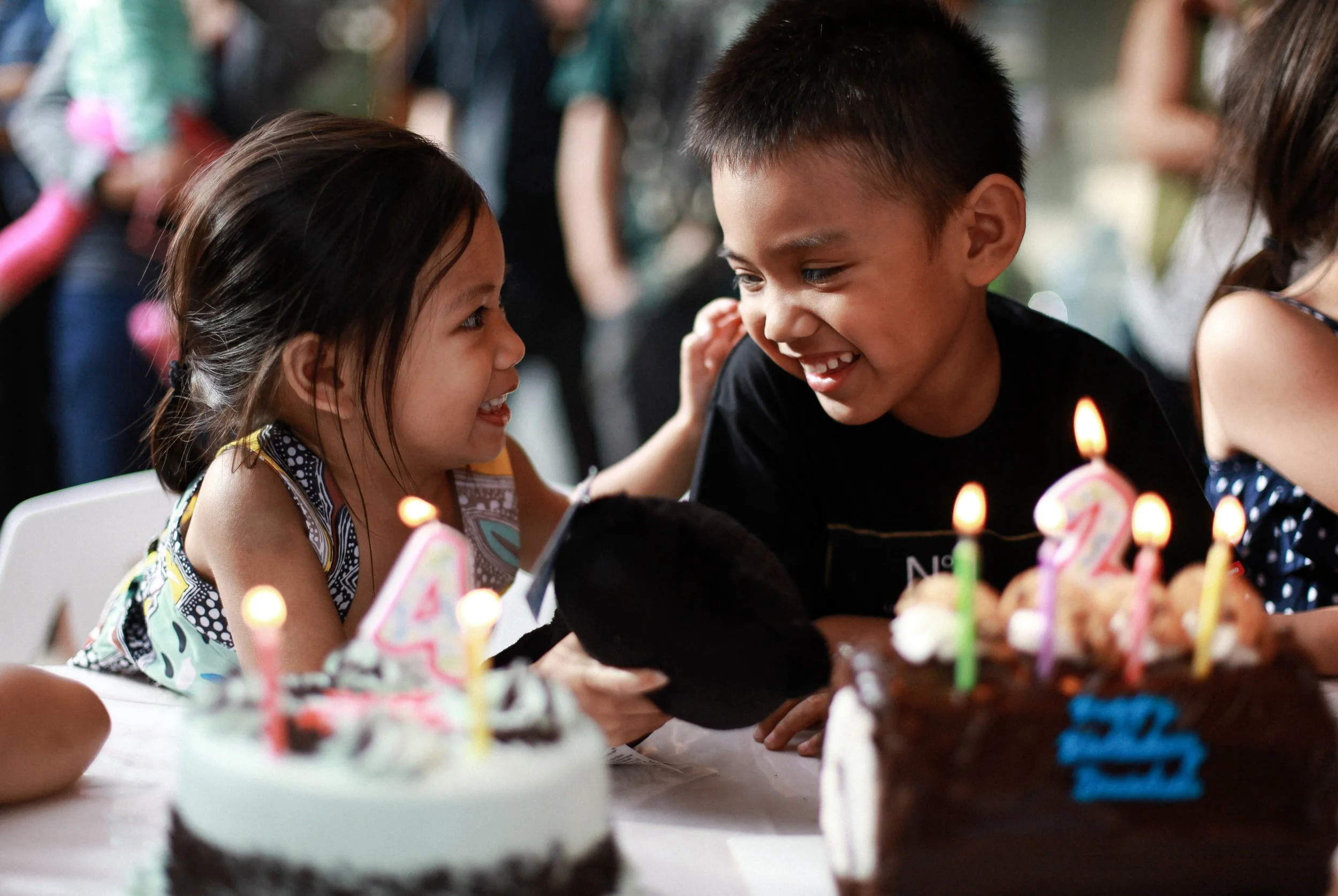 Children celebrating a birthday with a cake decorated with candles and birthday numbers, smiling and enjoying the moment.