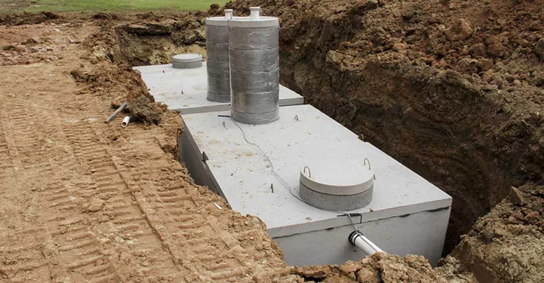 Underground utility box with pipes and ventilation pipes in a construction trench.