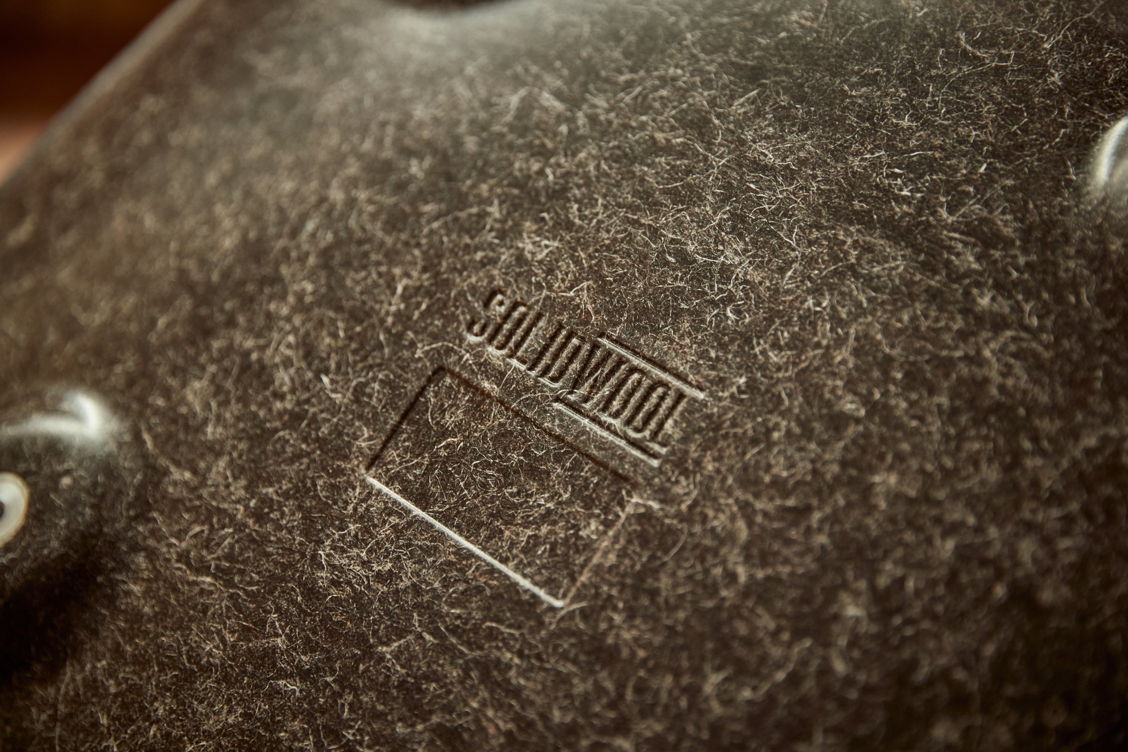 Close-up of a vintage brown leather object with an embossed brand name 'DODGE'