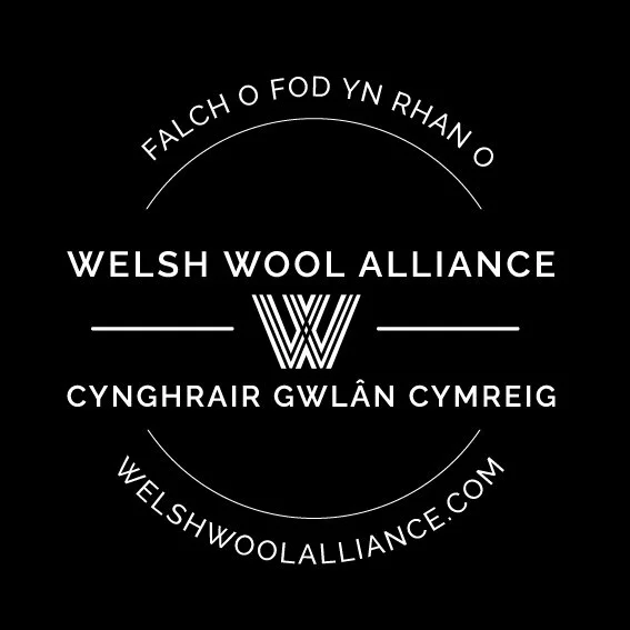 Black background with white circular logo for Welsh Wool Alliance, including Welsh and English text, a stylized 'W' in the center, and website URL welshwoollliance.com.