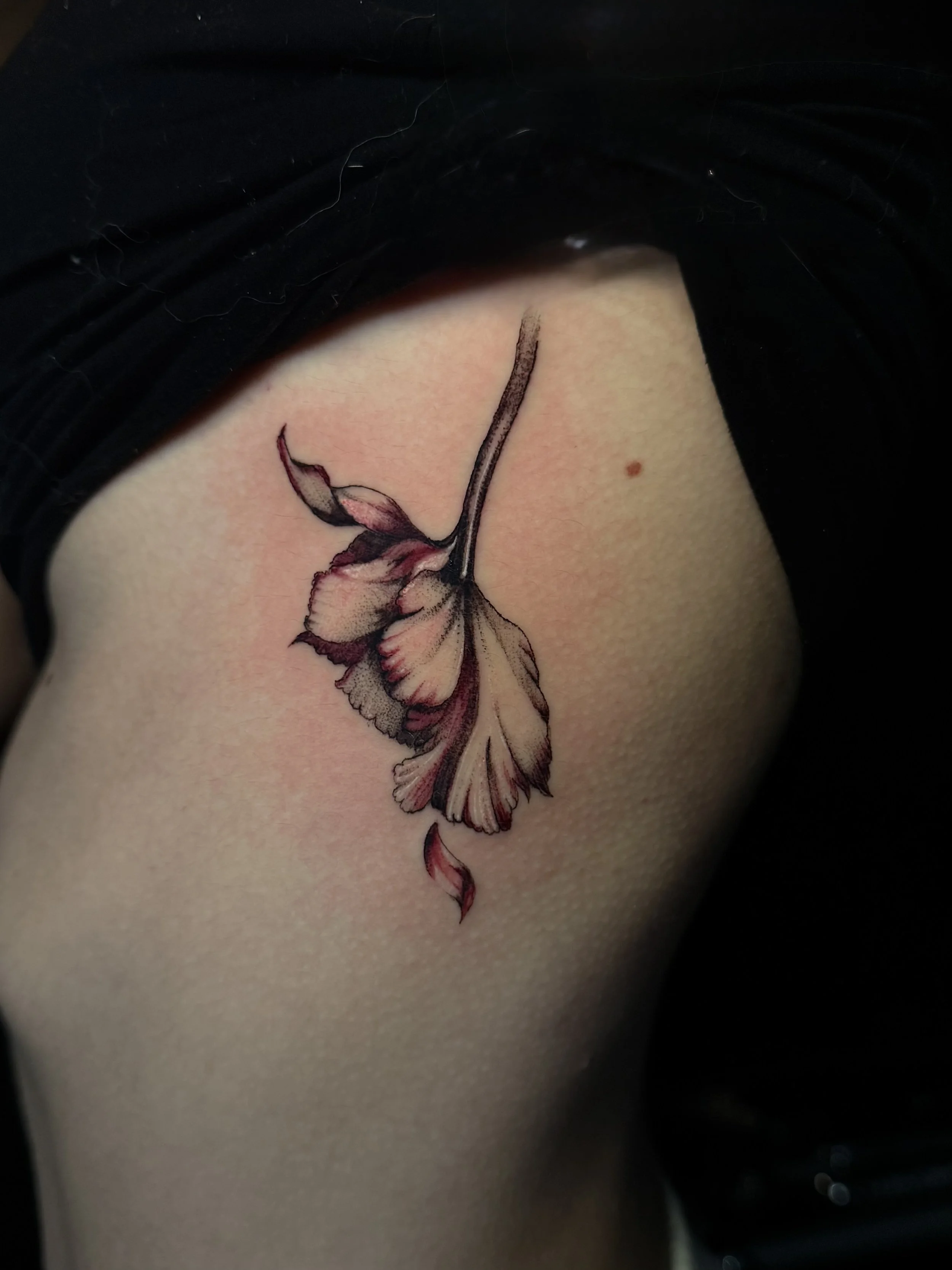 A tattoo of a detailed, colored flower on skin.