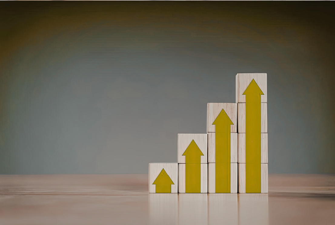 Stacked white blocks with yellow upward arrows, arranged in increasing height from left to right, on a wooden surface.