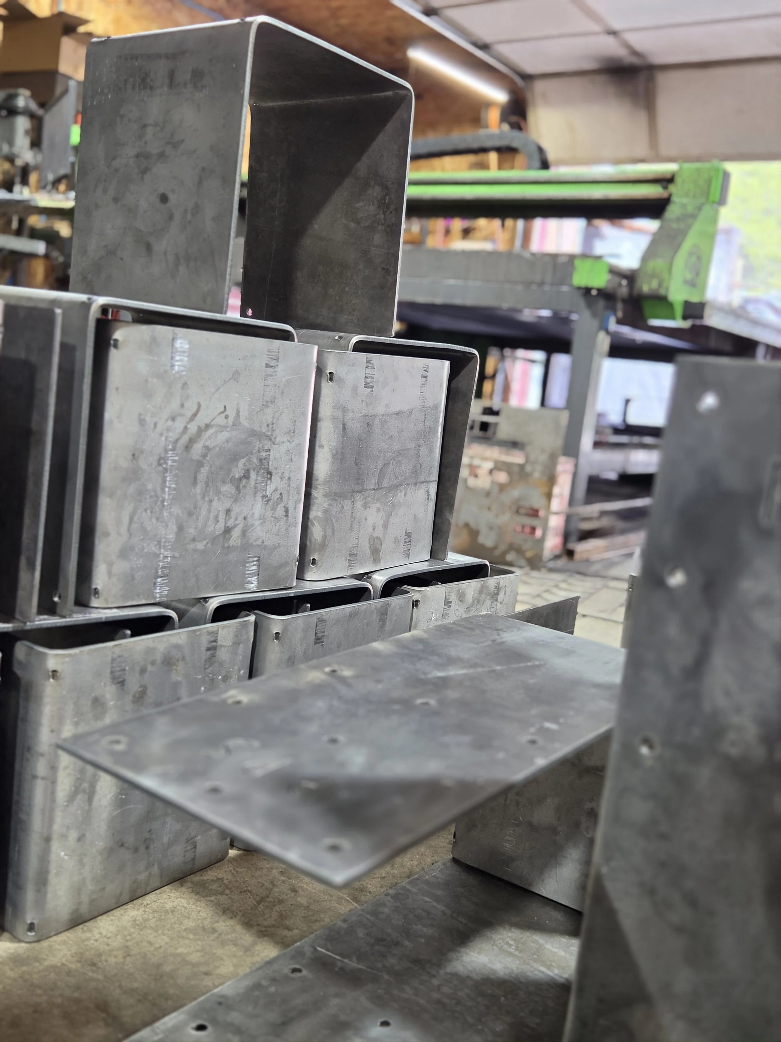 Metal molds or containers stacked in a workshop or factory environment.