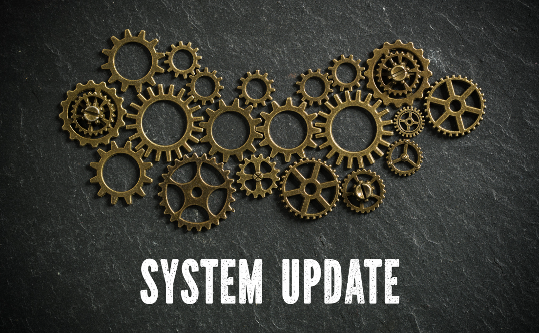 A collection of brass gears arranged on a dark, textured surface with the text 'System Update' below.