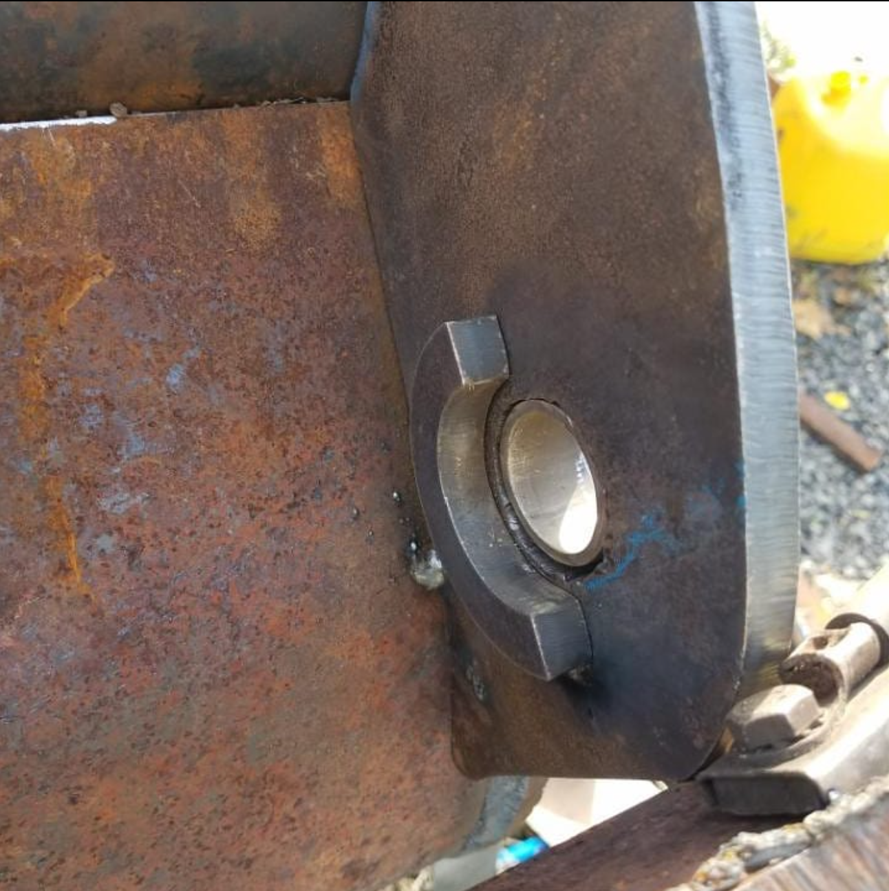 Close-up view of a metal bearing mounted on a rusted metal surface, with a black metal plate and bolts nearby.