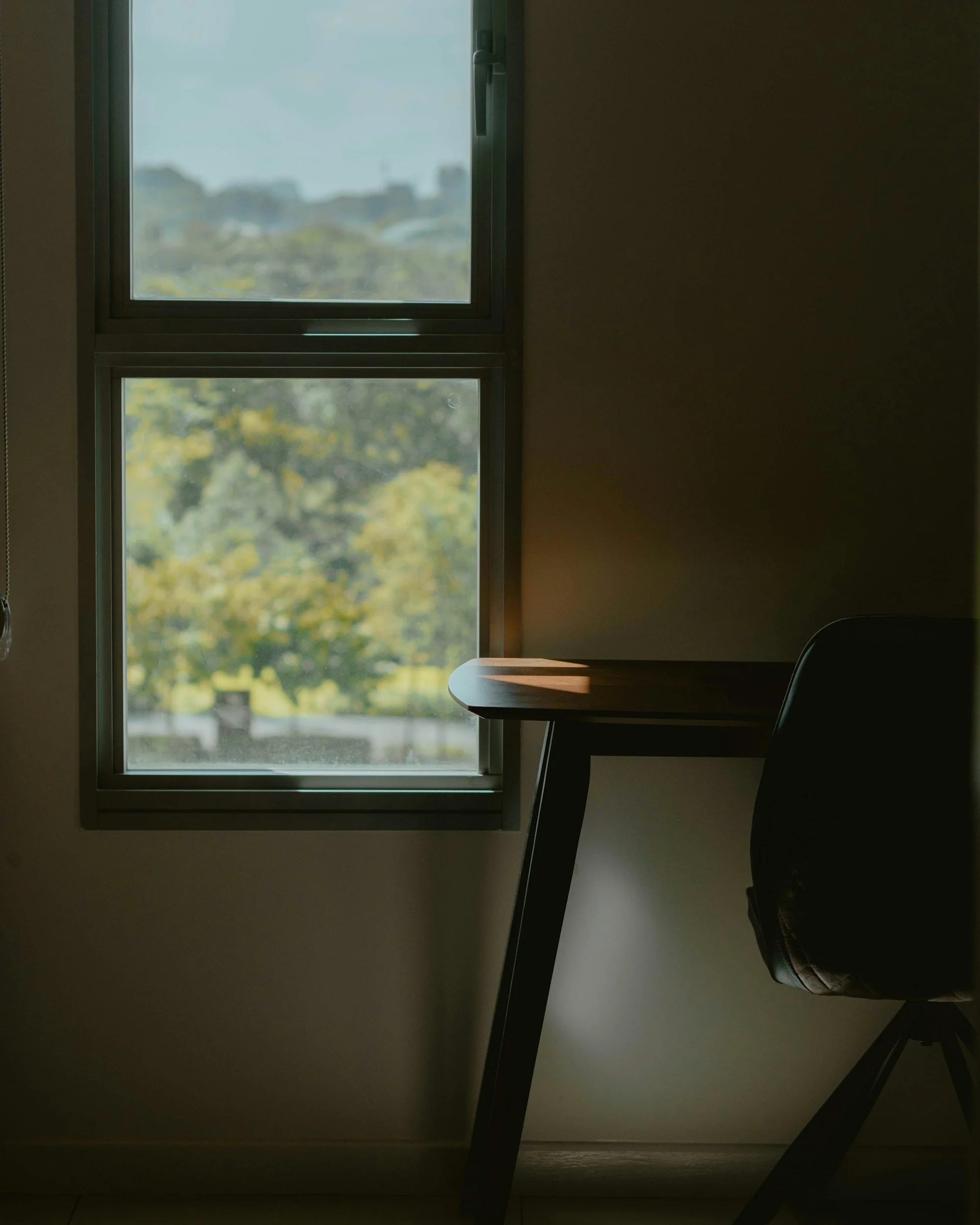 Sunlight coming through a window, illuminating a desk and chair in a room.