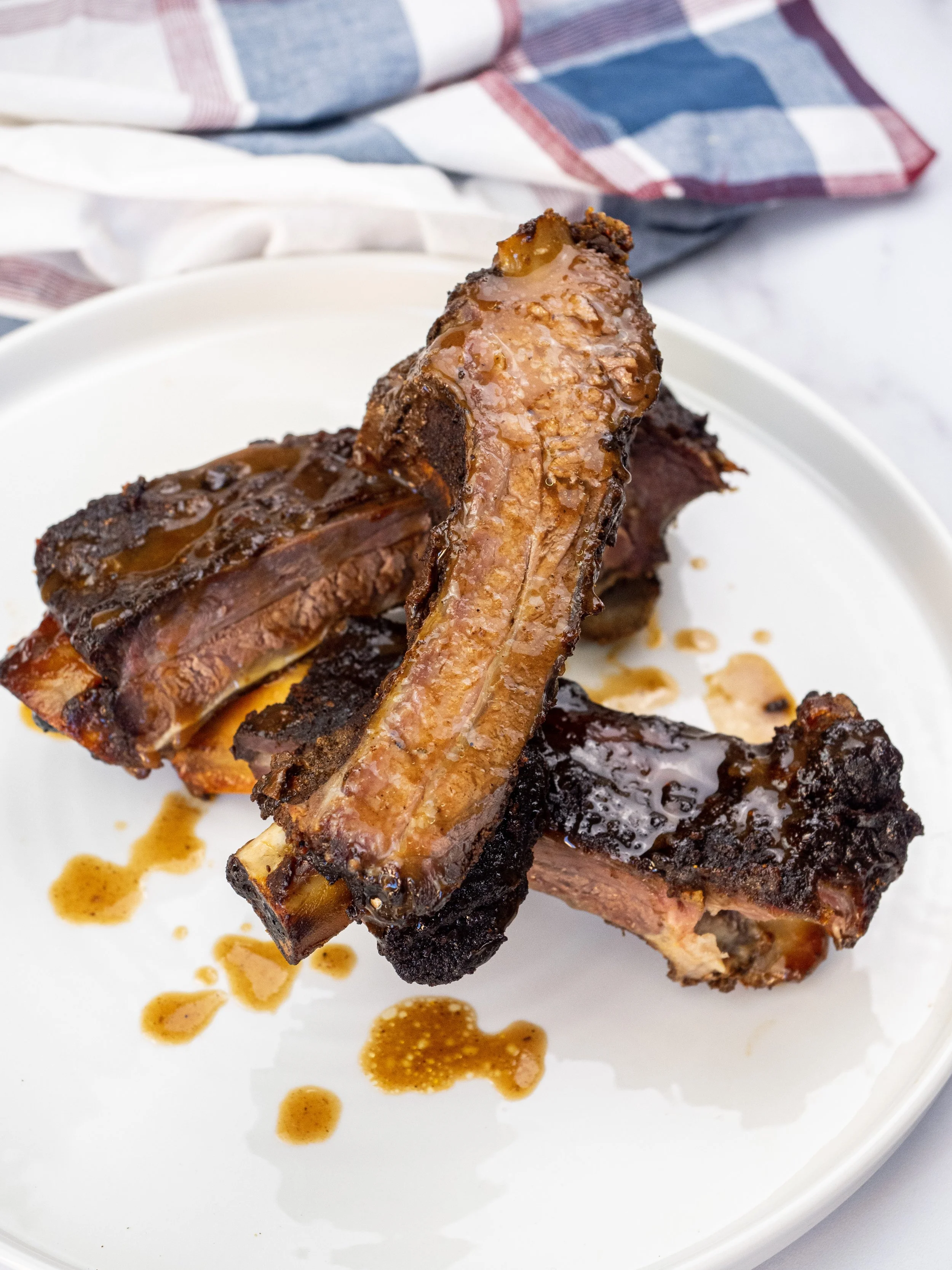 Barbecue beef back ribs on a white plate with barbecue sauce.