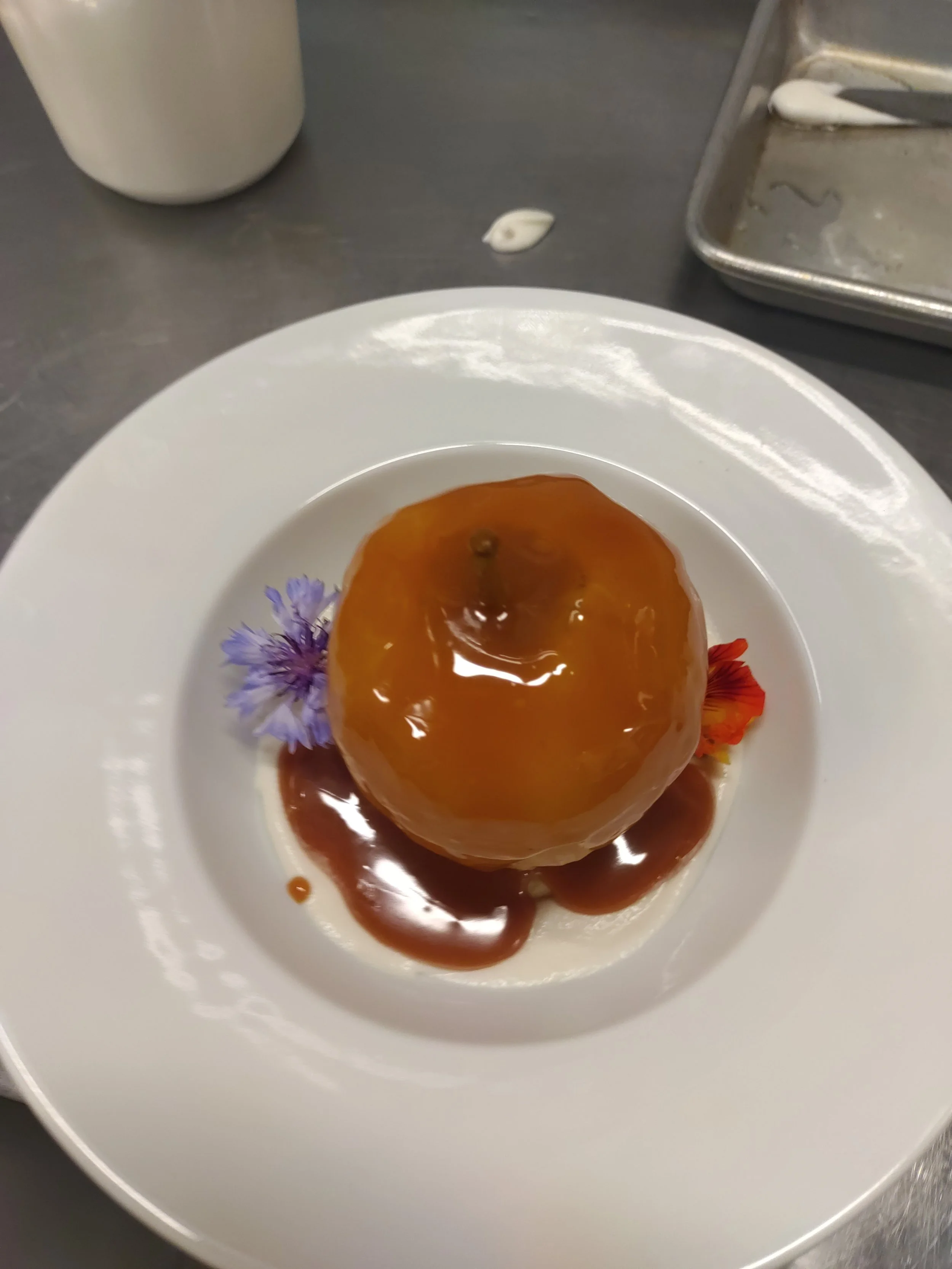 Rum Poached Apples topped with a Smoked-Caramel sauce, sitting in a bowl.