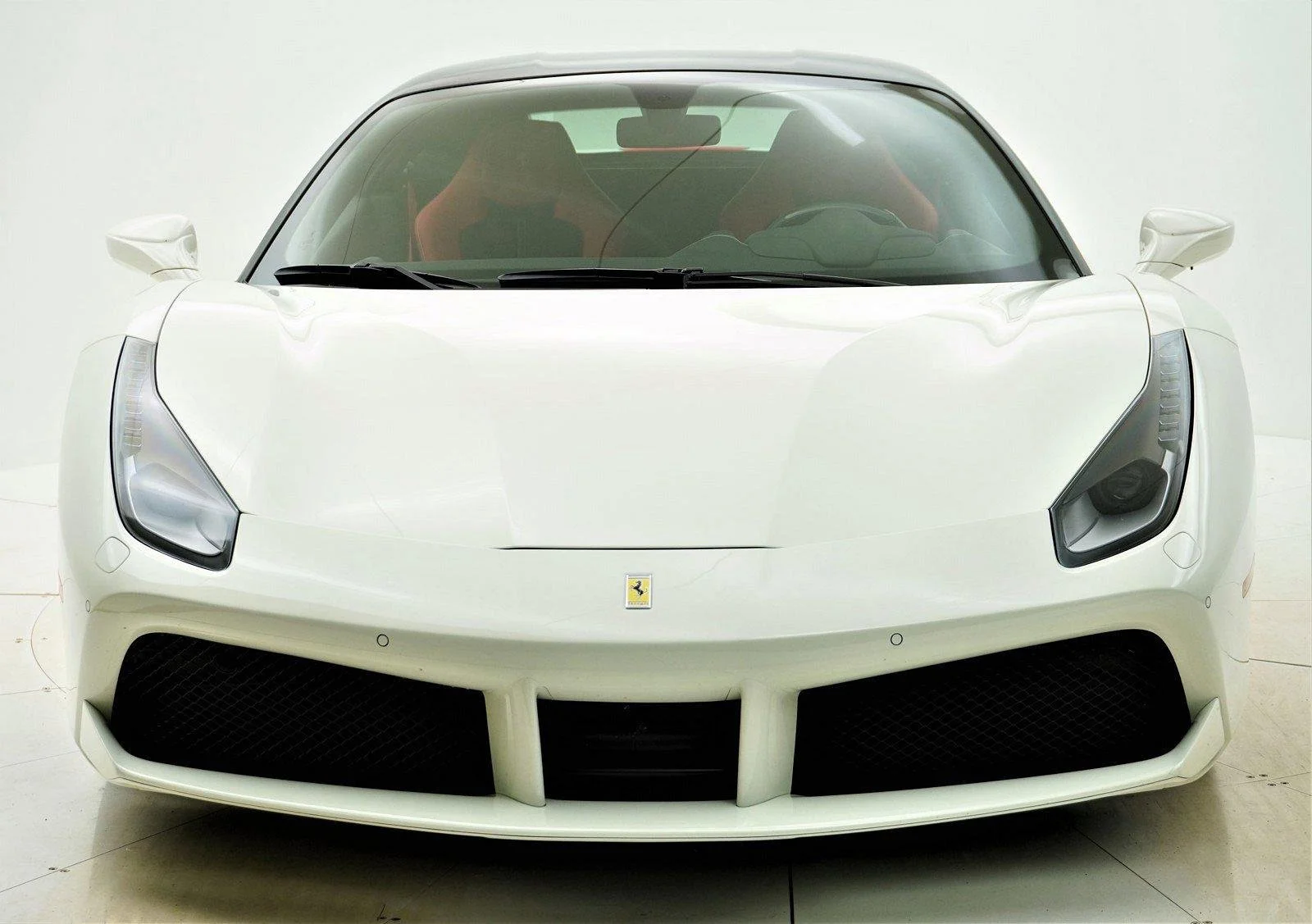 Front view of a white Ferrari sports car in a studio setting.