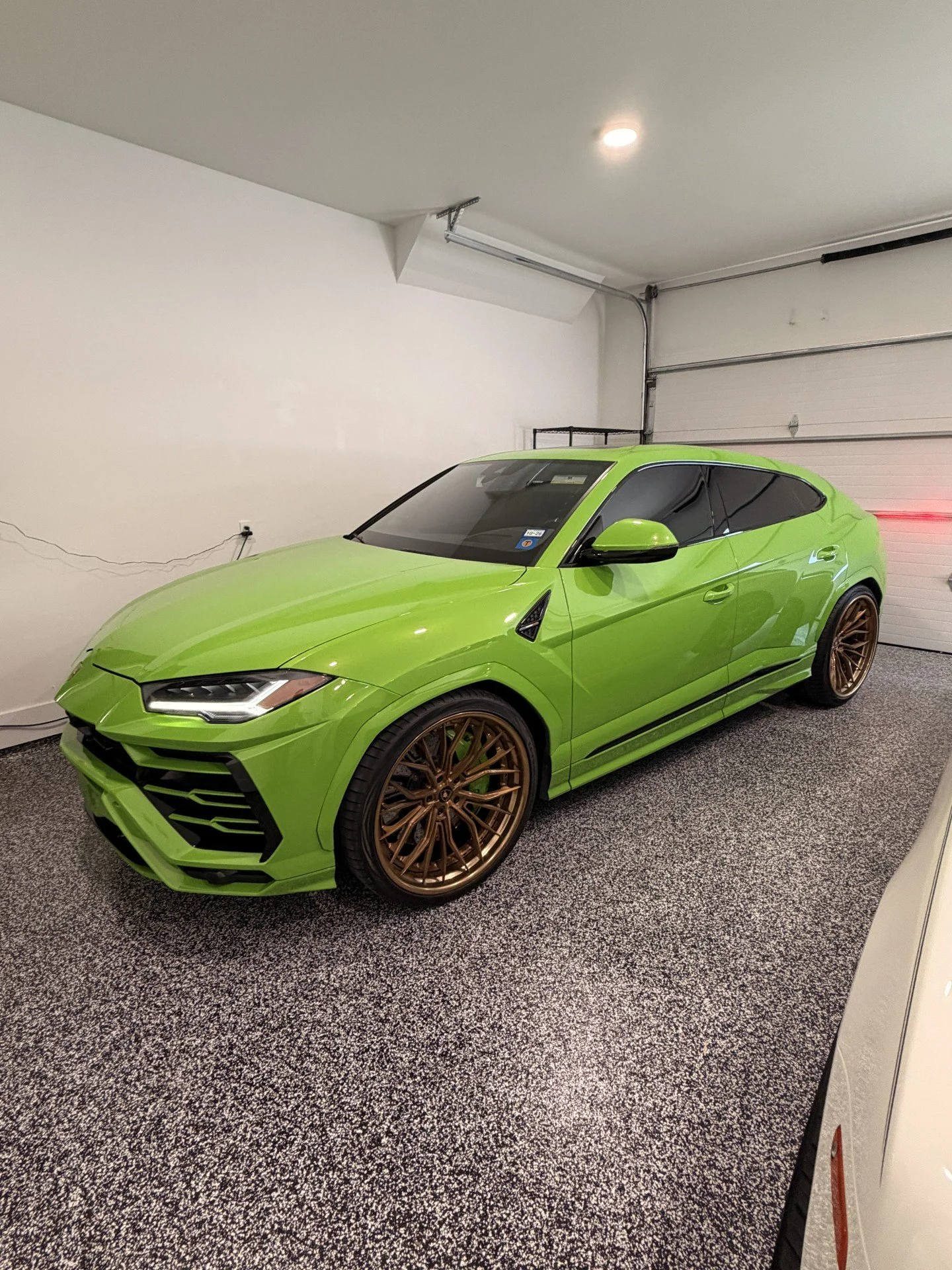 Green Lamborghini with bronze wheels parked in a garage.