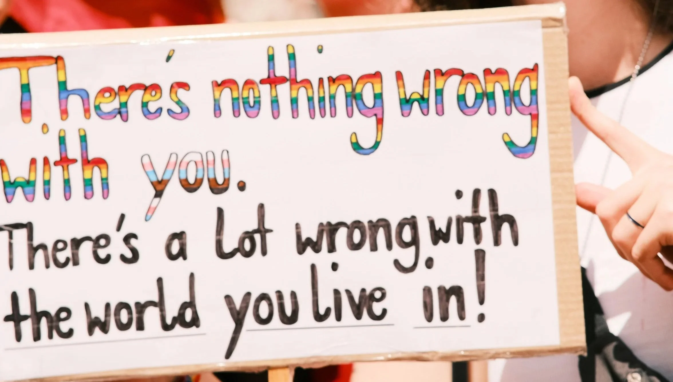 Drawn sign with the words 'there is nothing wrong with you. there's a lot wrong with the world you live in!', written in pride colors