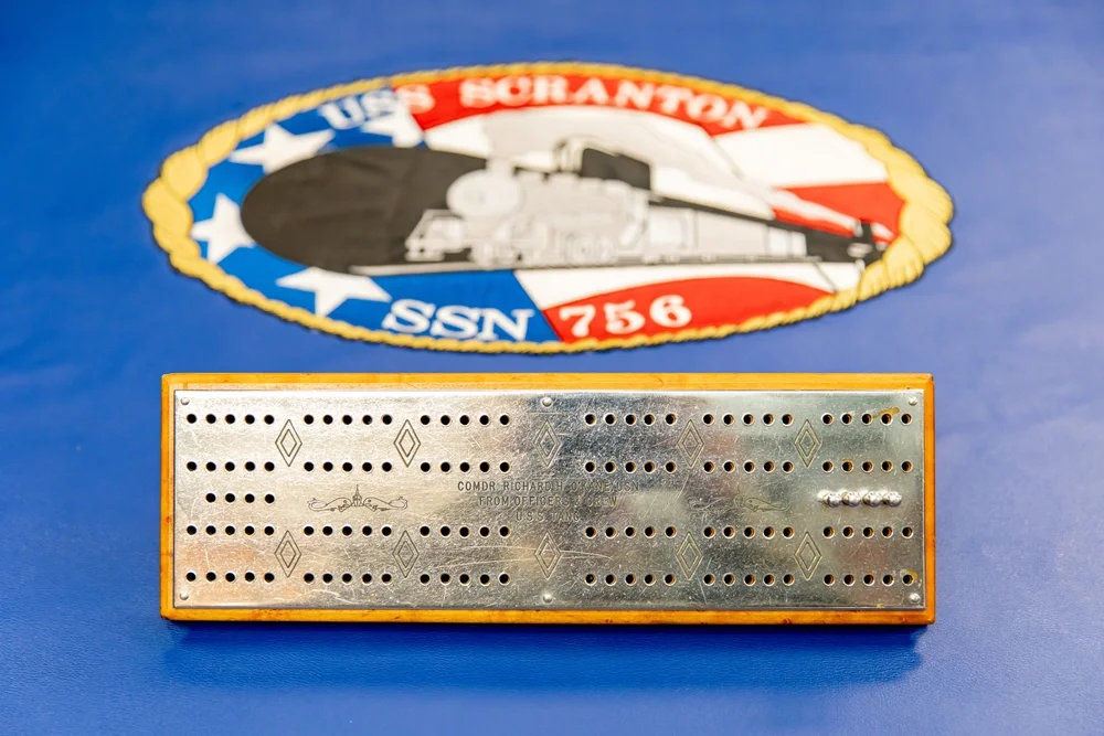 Admiral Okane's cribbage board with the current ship's crest it is on.