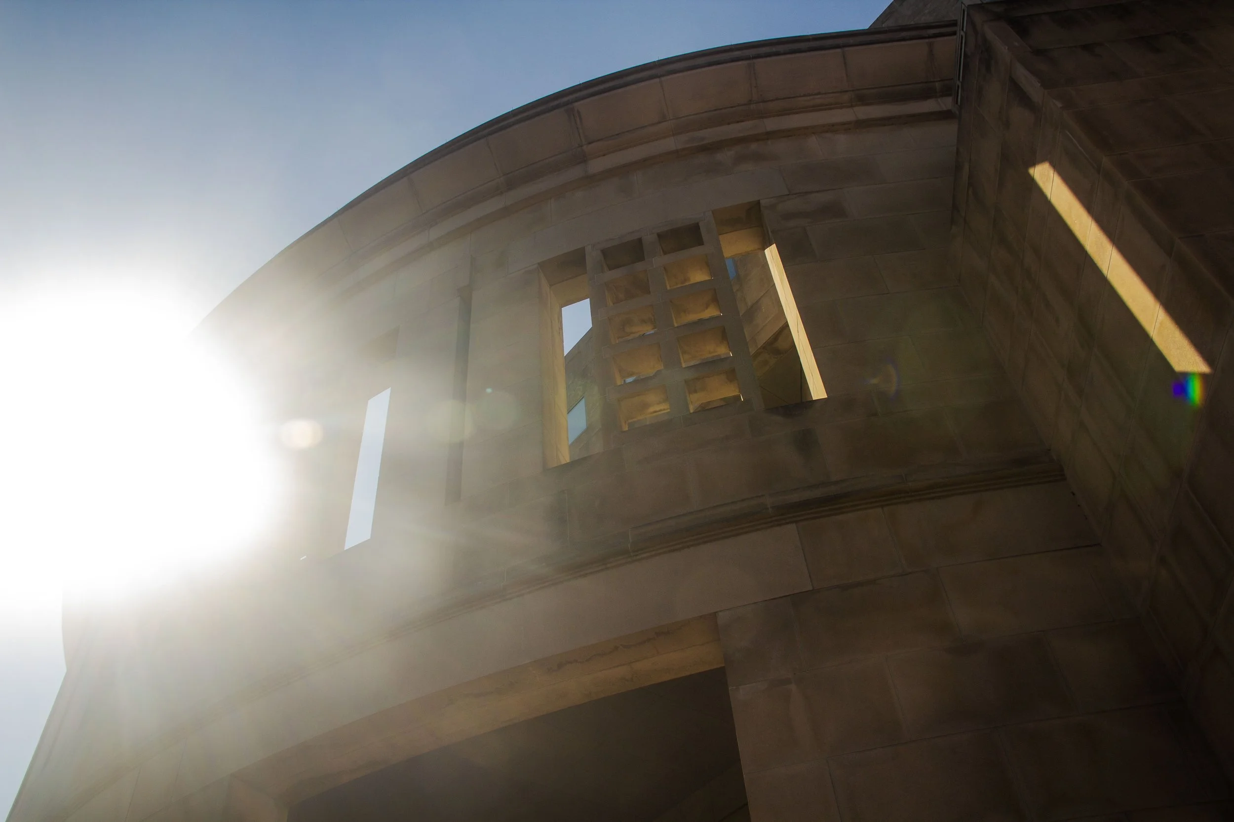 Architectural detail of a building with curved structure and openings, bathed in sunlight.