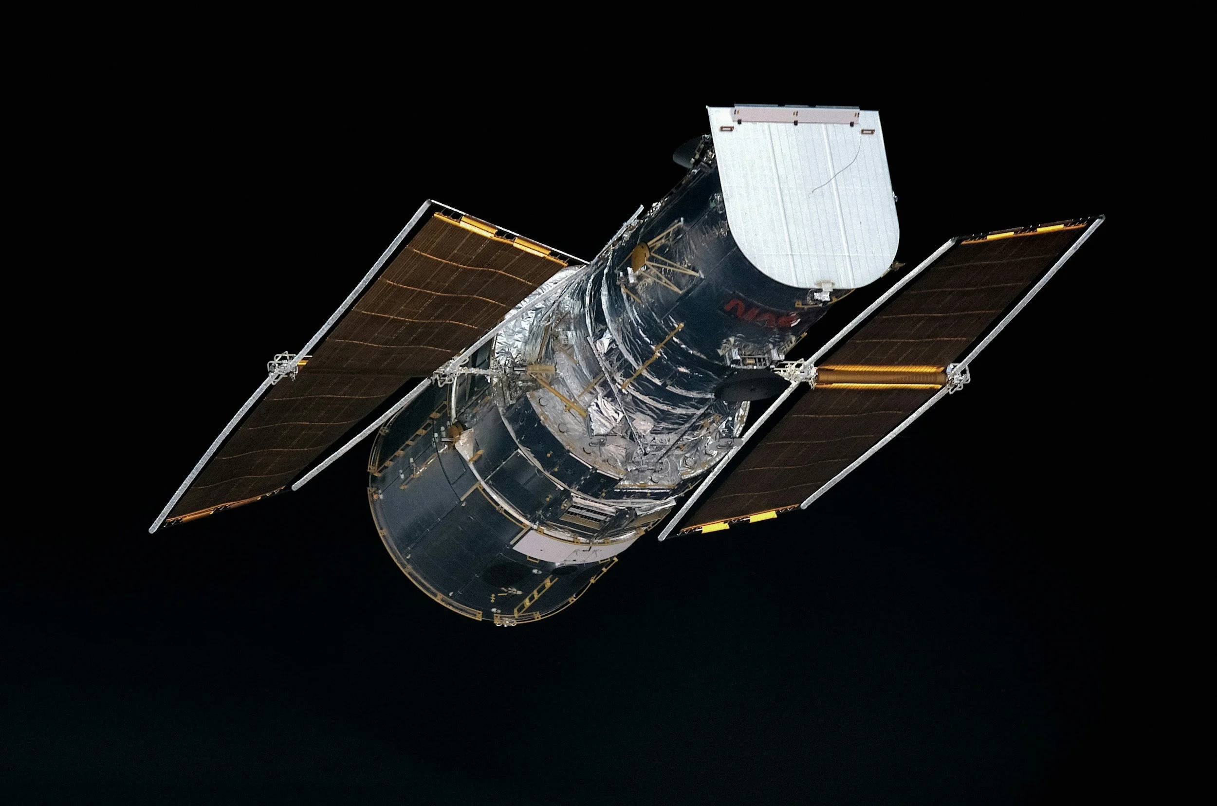 A satellite with solar panels extended, orbiting in space against a black background.