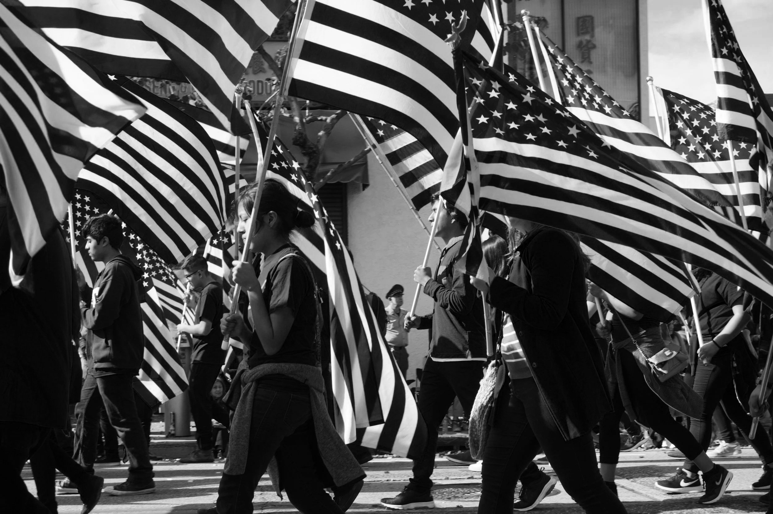 A crowd of people marching with American flags during a protest or parade.