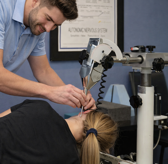 A person performing a medical procedure on a patient using a robotic surgical arm in a clinical setting.