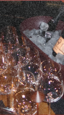 Several glasses of champagne on a table with ice in a bucket, and a cork and bottle opener nearby.