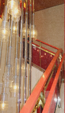 Interior view of a staircase with red railing and modern pendant lights hanging from the ceiling.