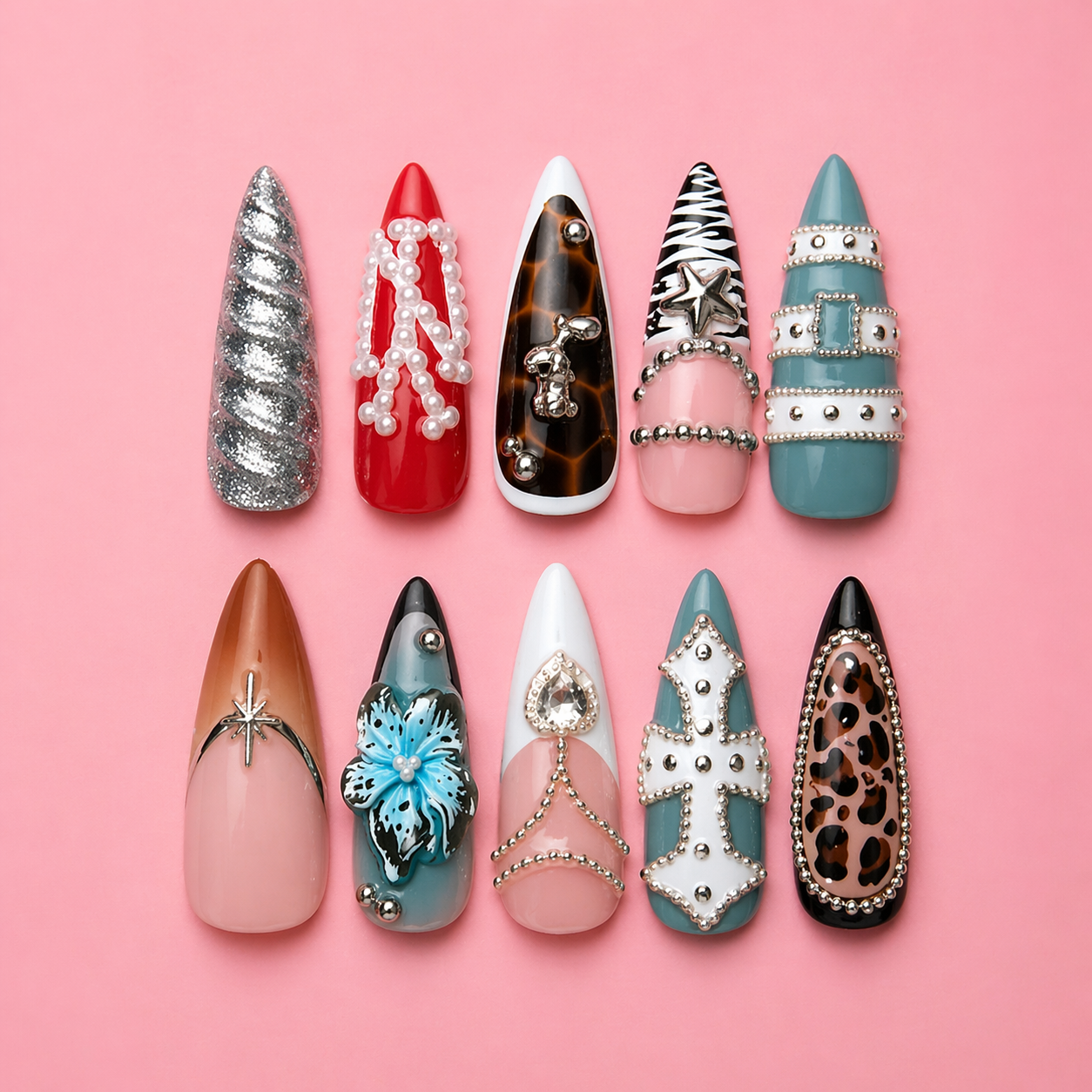 Two rows of decorative false nails with various designs and embellishments on a pink background.