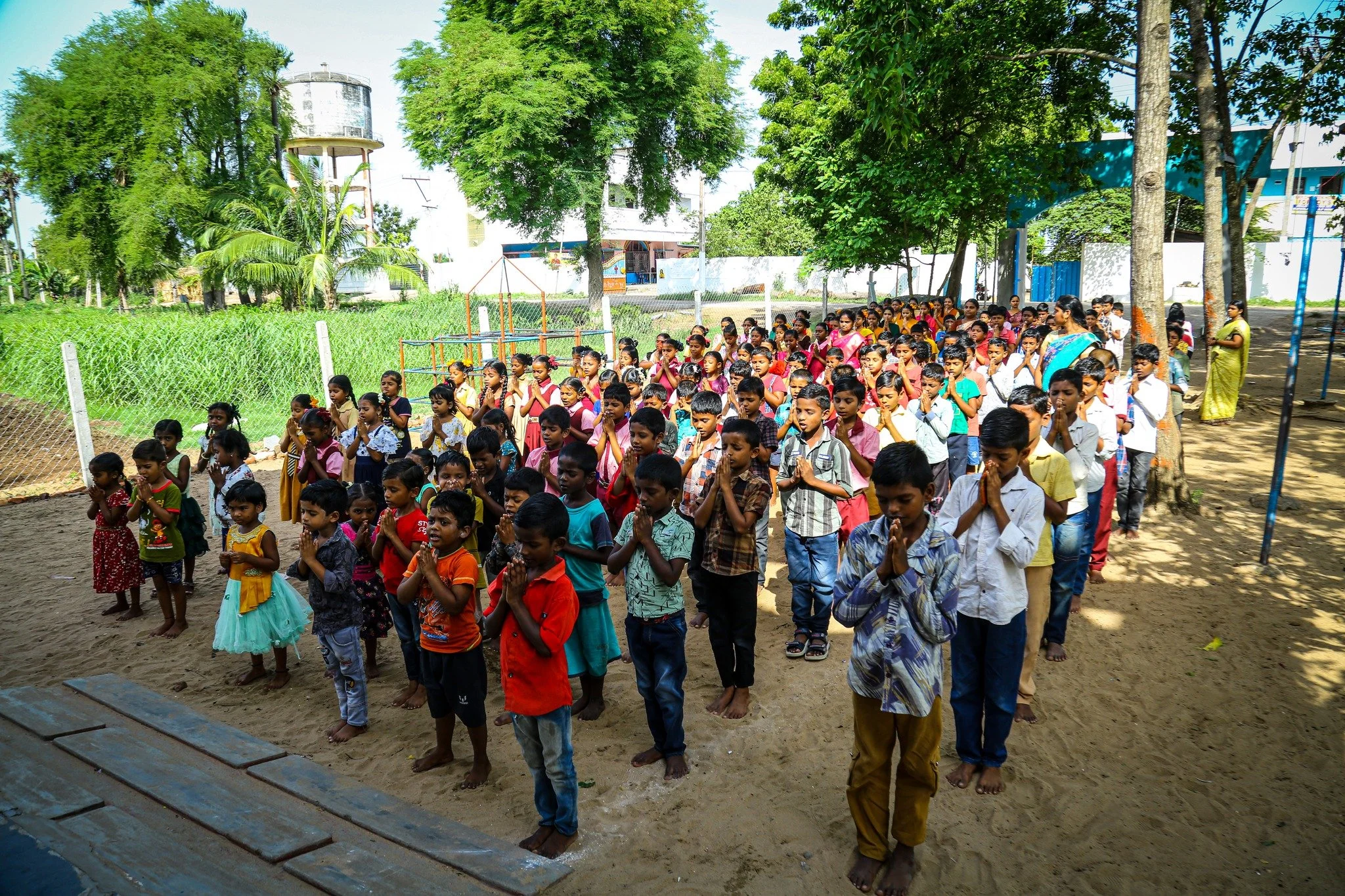 Group of children standing outdoors in a prayer position