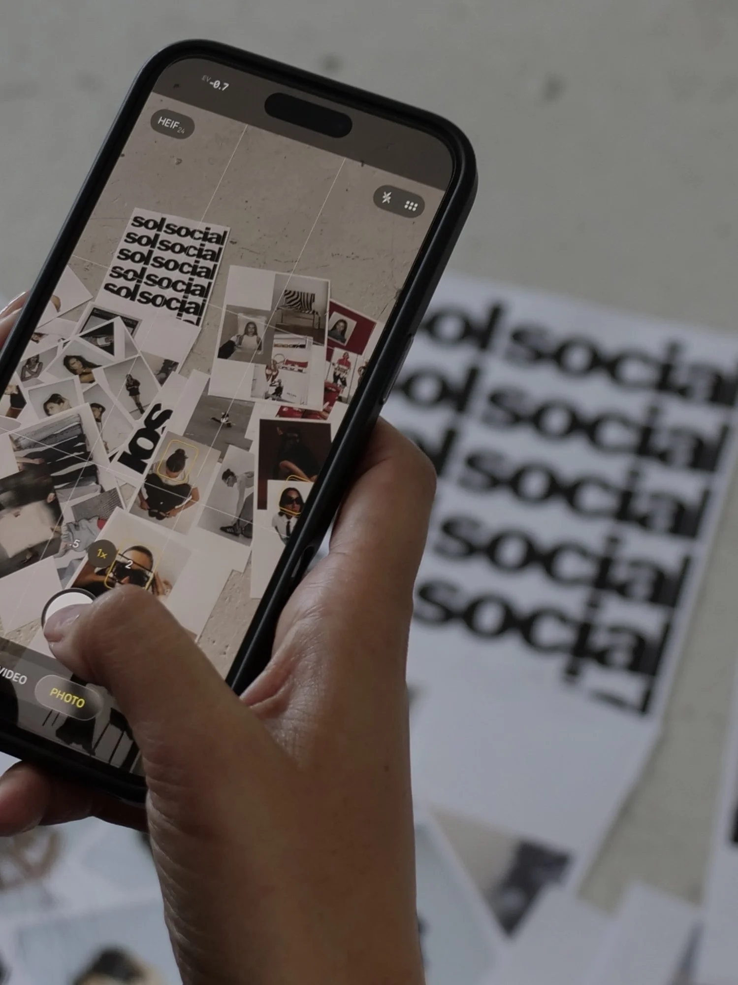 A person taking a photo with a smartphone of a collage of black and white photographs and text on a white background.