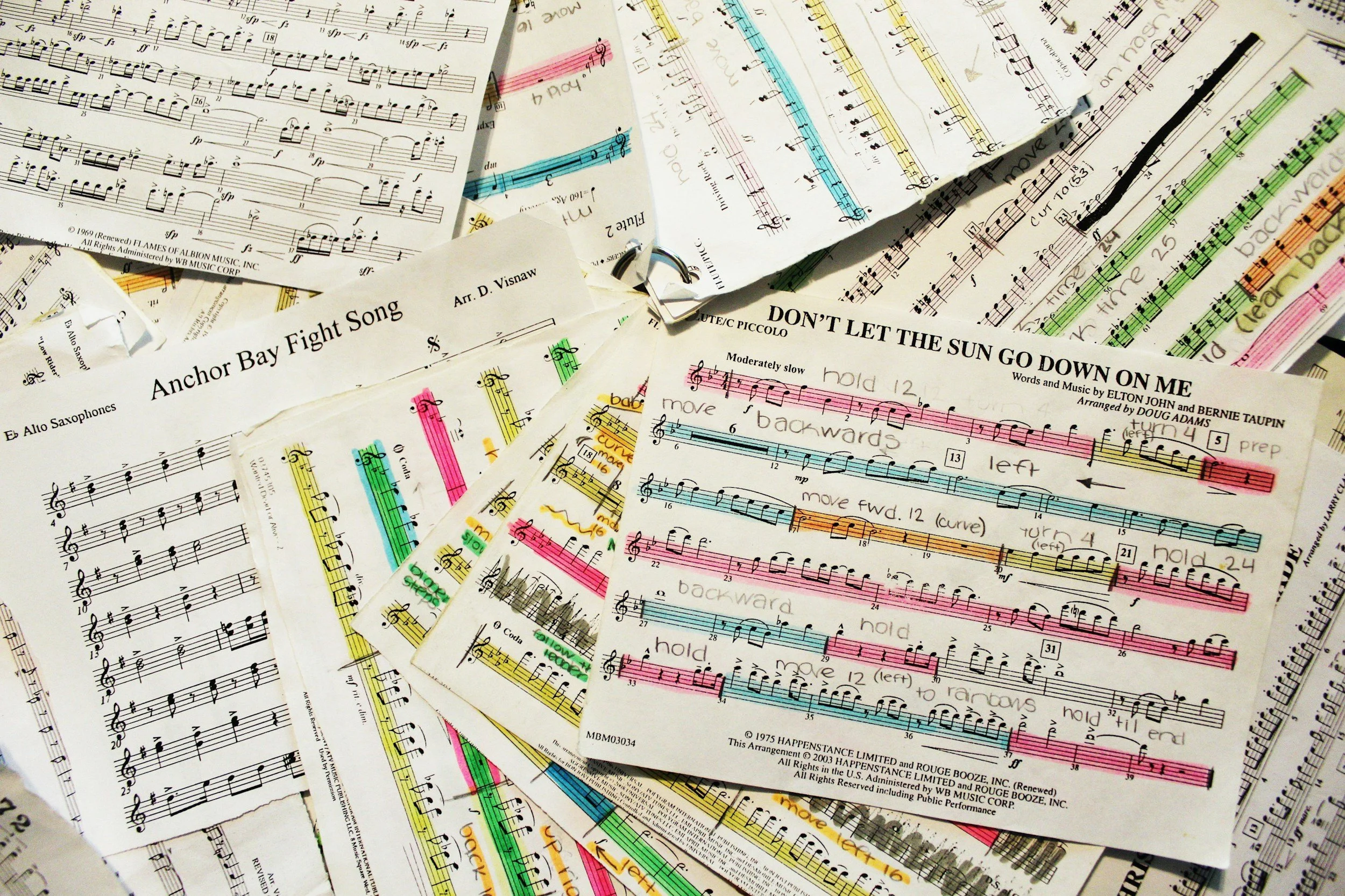 A collection of sheet music pages, some with colored markings and annotations, including musical notes, lyrics, and instructions for performance.