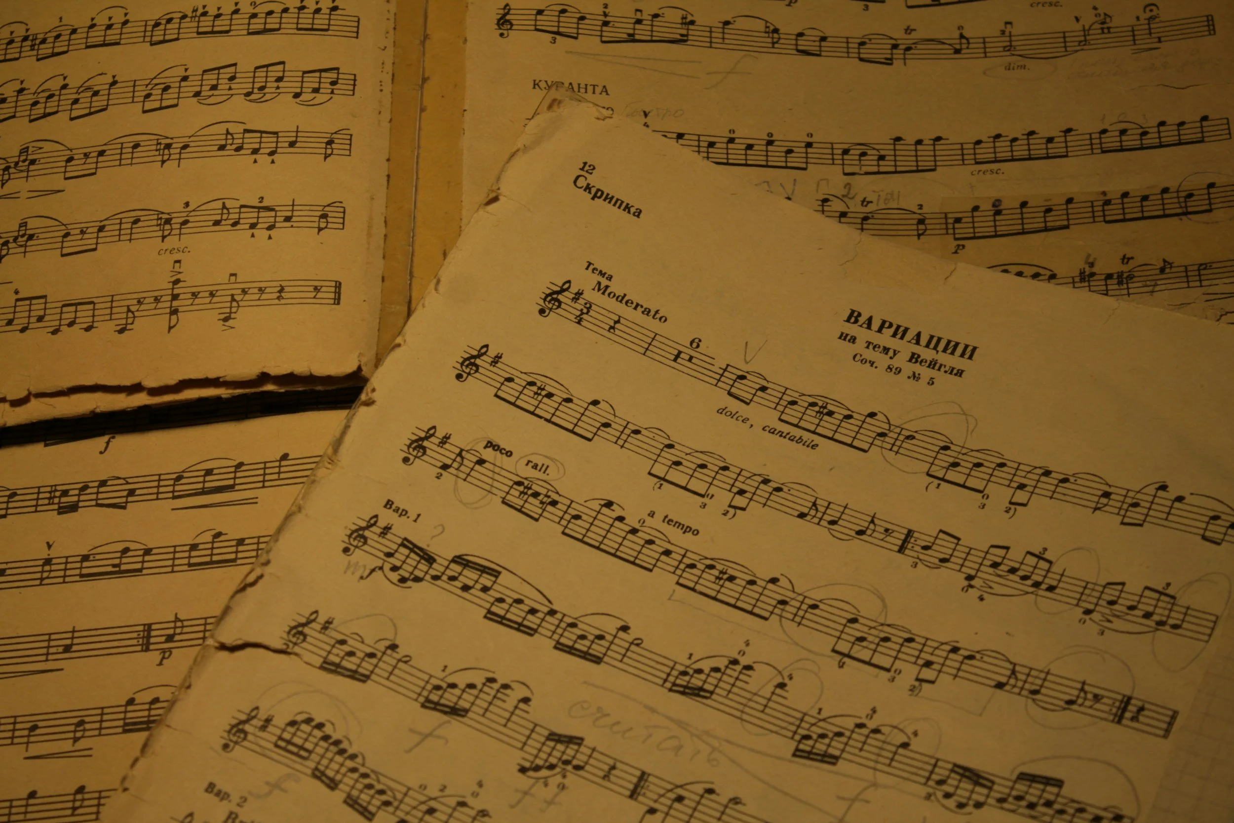 Open sheet music with handwritten notes, titled in Russian, with visible musical notation and torn edges.