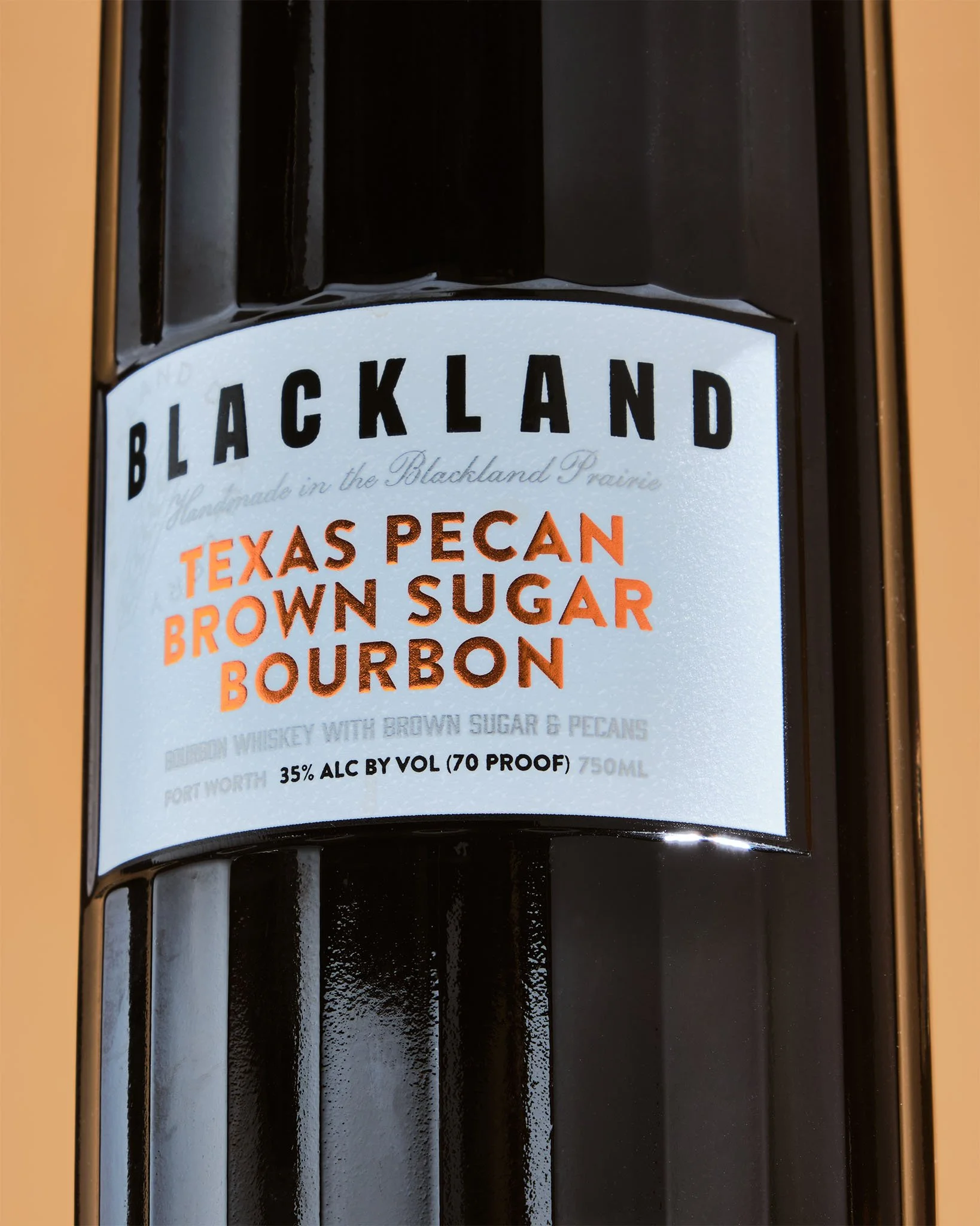 Close-up of a liquor bottle label for Blackland Texas Pecan Brown Sugar Bourbon, 750ml, 35% alcohol by volume, handcrafted in the Blackland Prairie.