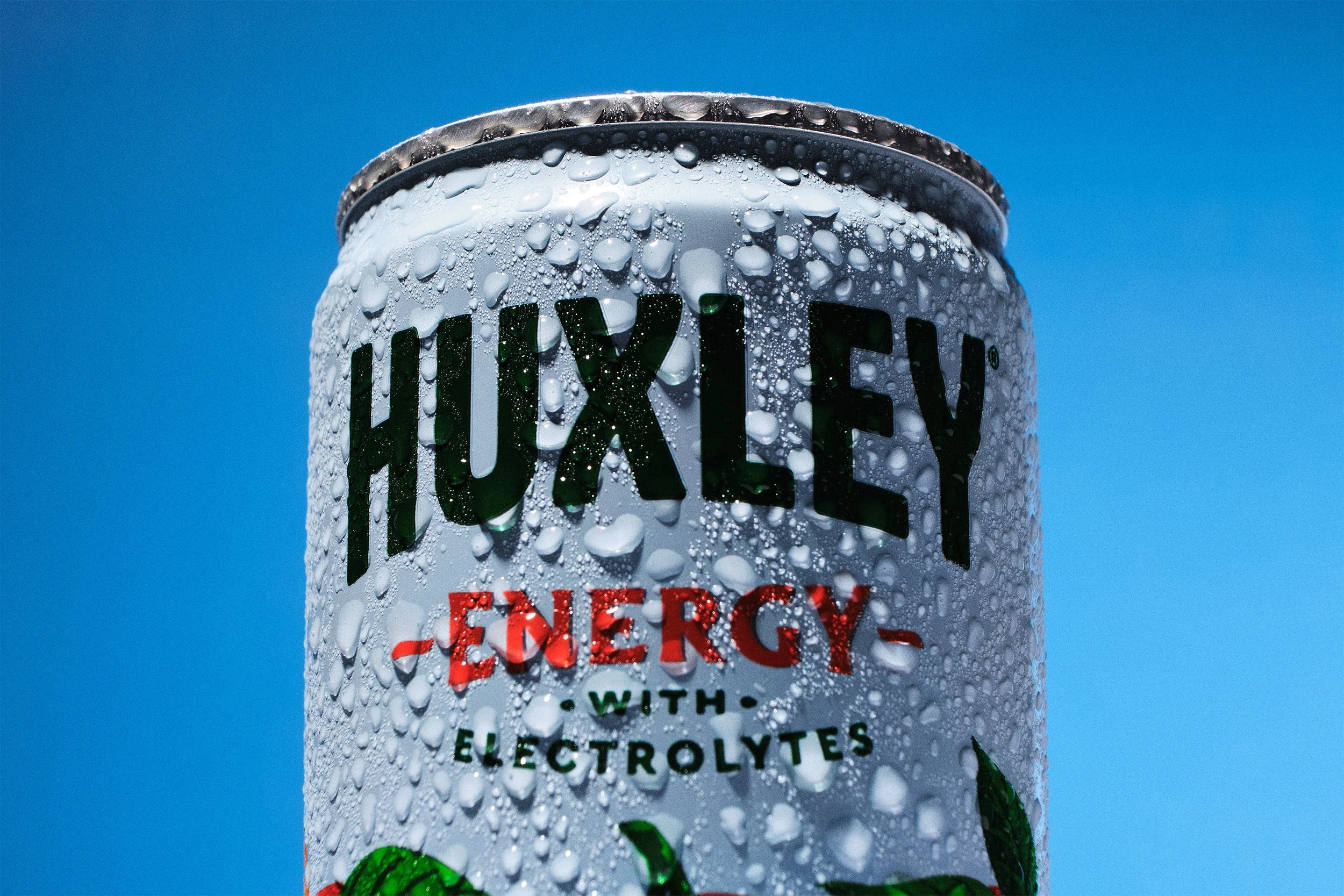 Close-up of a can of VIXTEK energy drink covered in water droplets, against a clear blue sky.