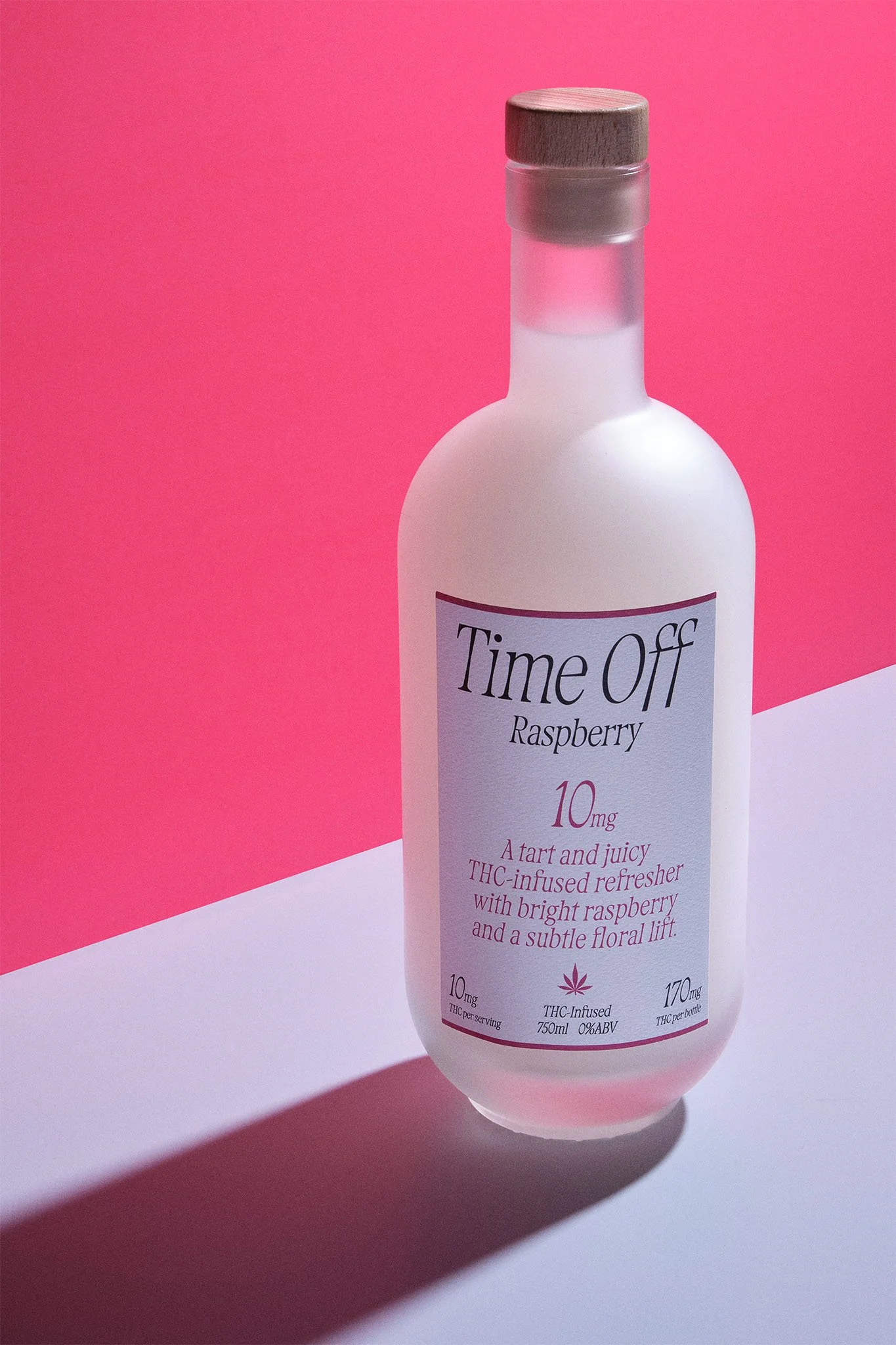 A white bottle with a wooden cap labeled 'Time Off Raspberry,' a THC-infused raspberry refresher with bright raspberry flavor and floral lift, on a pink and white background.