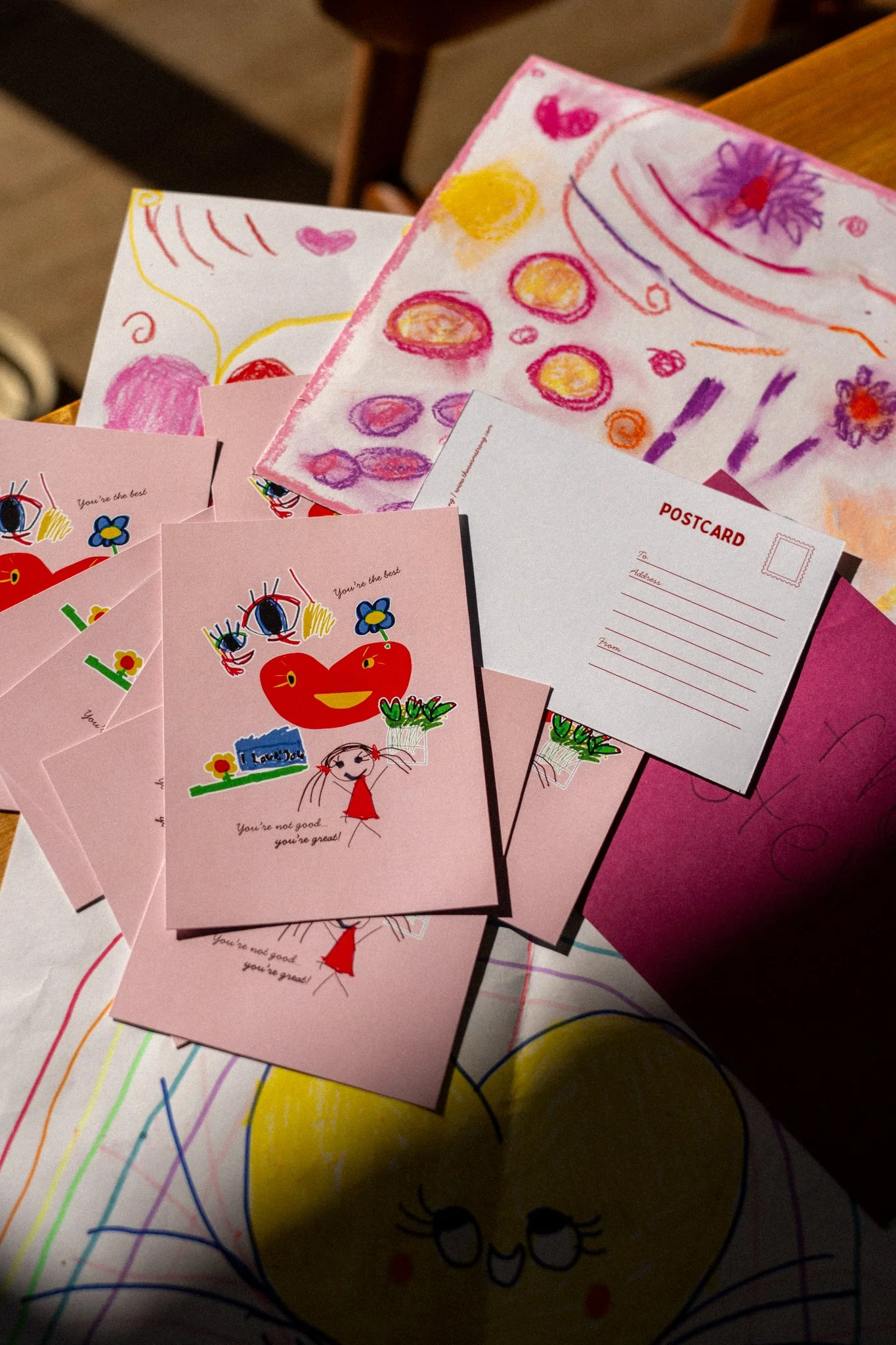 Colorful drawings and postcards on a table, featuring flowers, smiley faces, and various abstract designs in bright colors.