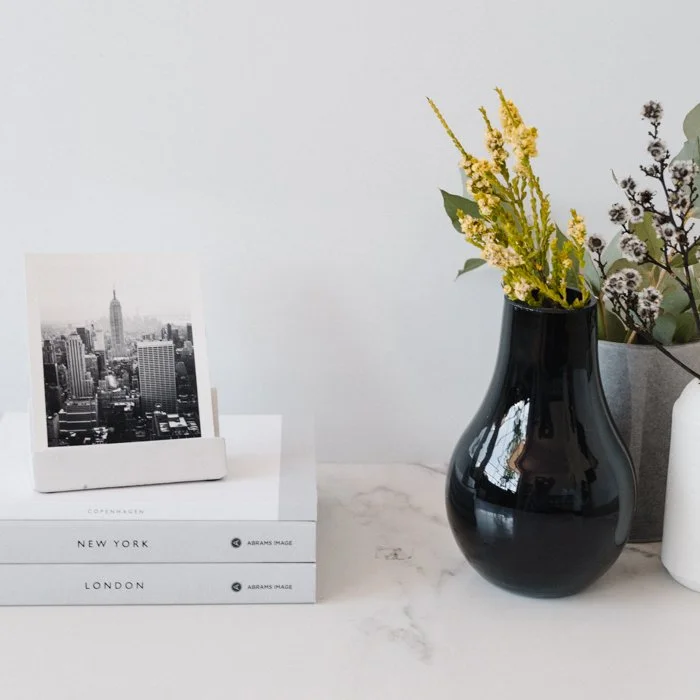 Black and white travel photograph displayed as a fine art print in a styled interior setting with books and flowers.