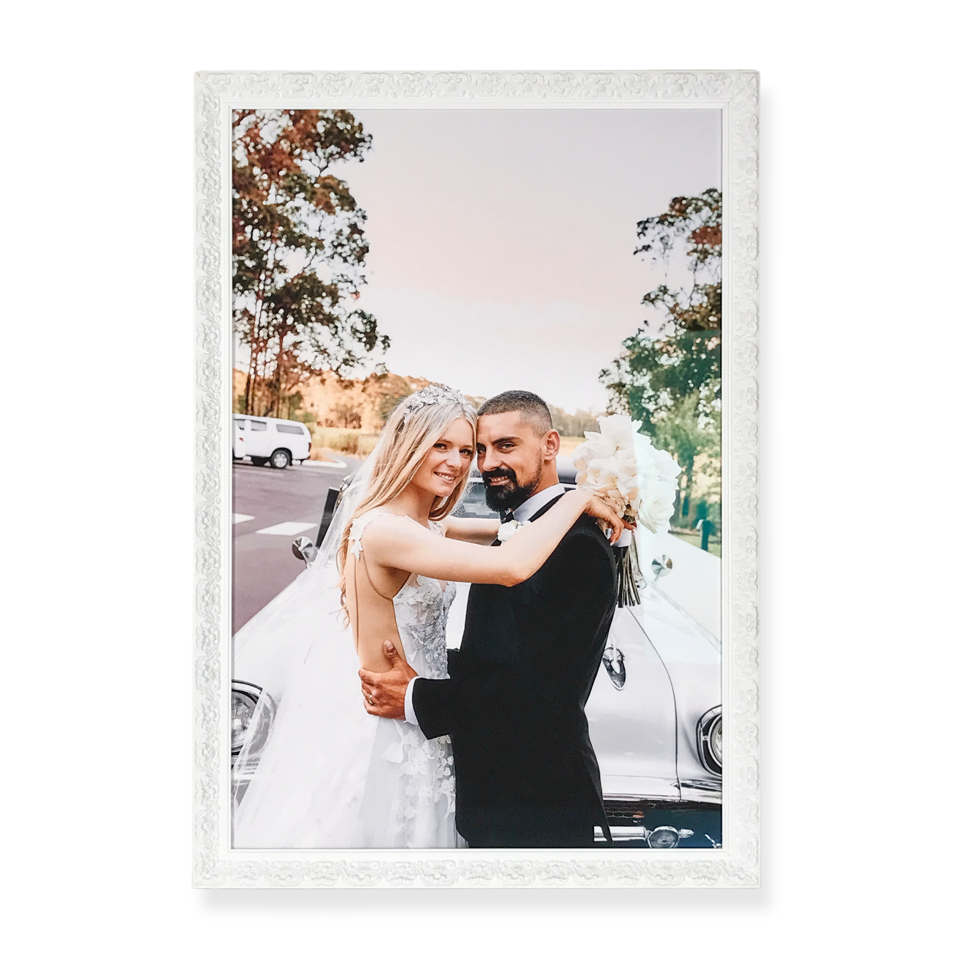 wedding photograph print featuring a bride and groom embracing during an outdoor wedding celebration, framed in a vintage white frame. 