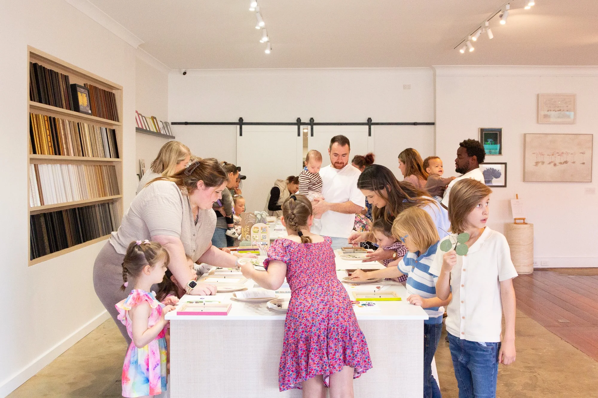 Children and adults creating pressed flower frames during the Mother’s Day community pop-up event at Framed in Bunbury.