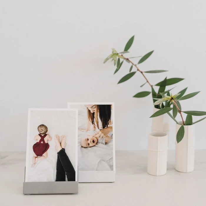 Postcard-size fine art prints displayed in modern tabletop stands, featuring family photography and lifestyle portraits printed by Framed in Australia.