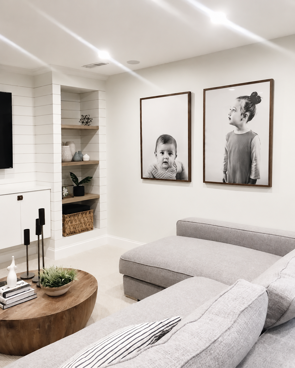Black and white family portrait prints displayed in a modern living room, showcasing custom framed photo printing by Framed in Australia.