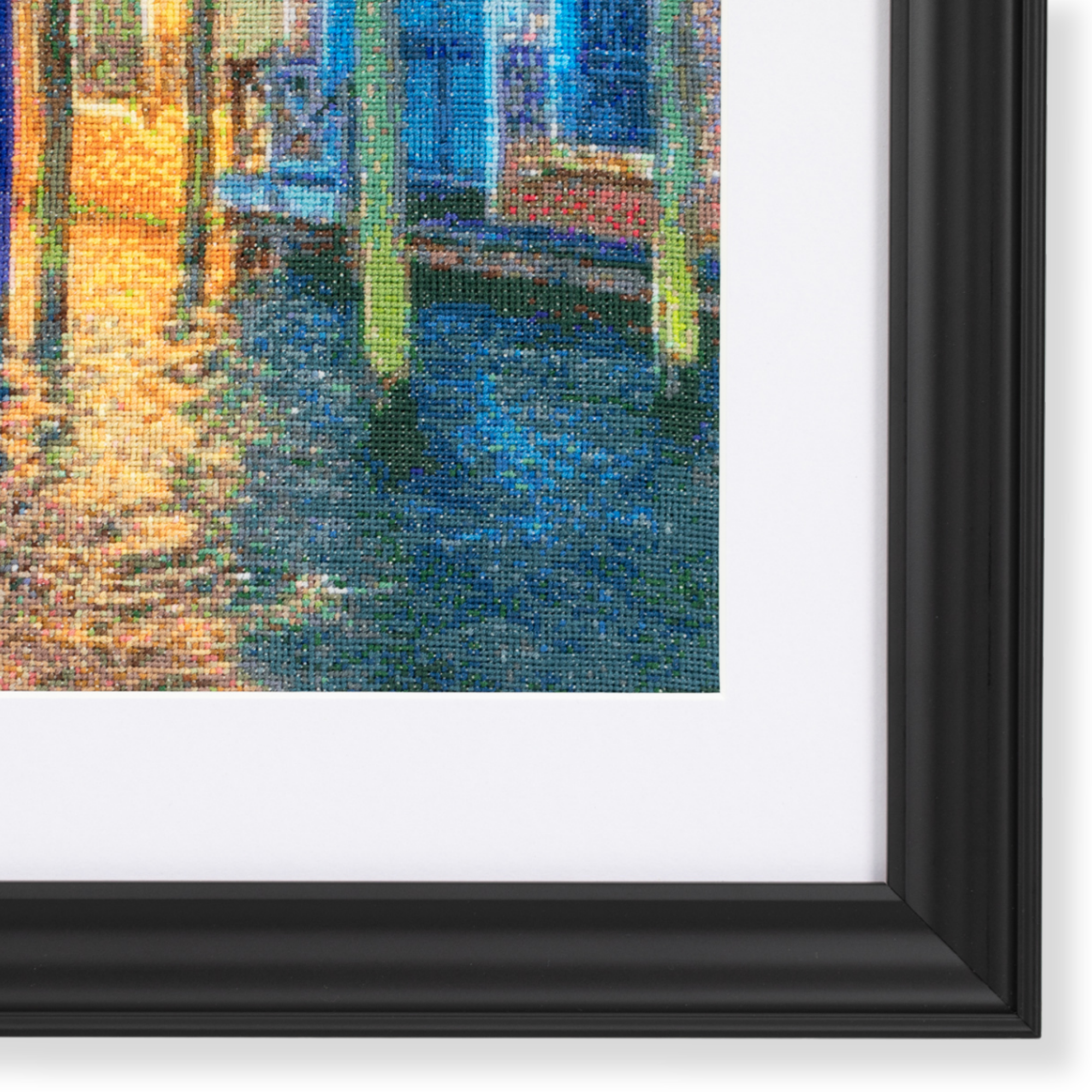 Close-up of custom framing detail featuring a Venice cross stitch artwork with white matting and a black contemporary frame.