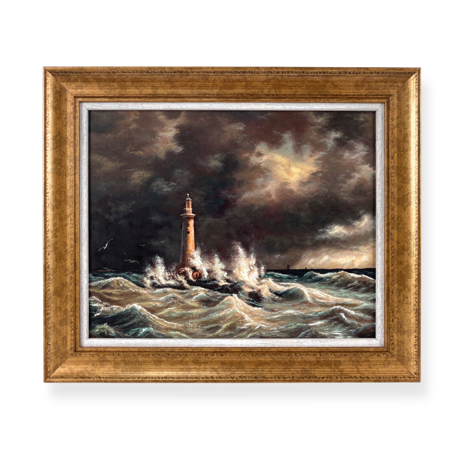 Framed lighthouse oil painting featuring dramatic ocean waves and stormy coastal skies. Double framed with white timber and gold frame. 