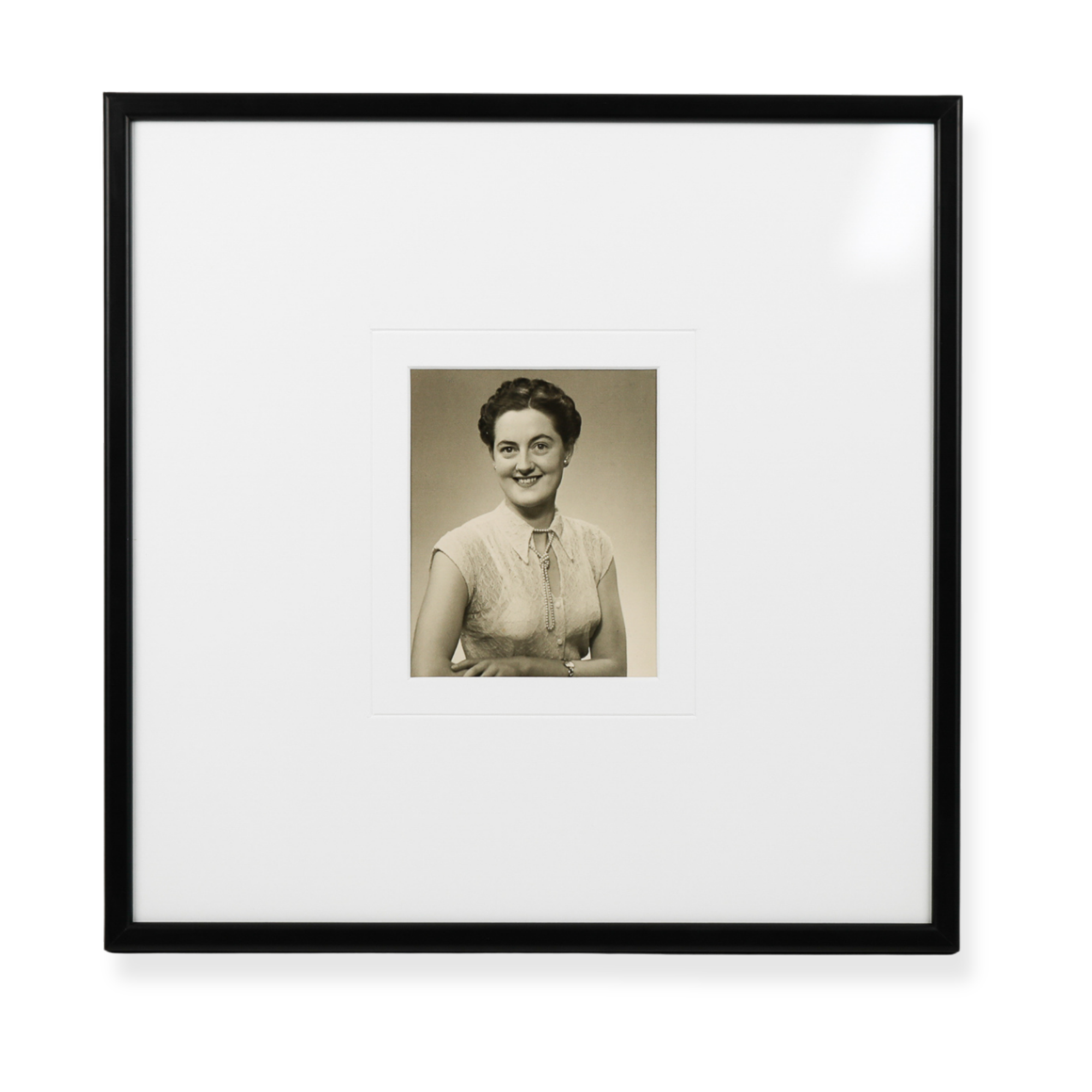 Framed vintage black and white portrait photograph displayed in a minimalist black frame with oversized matting.