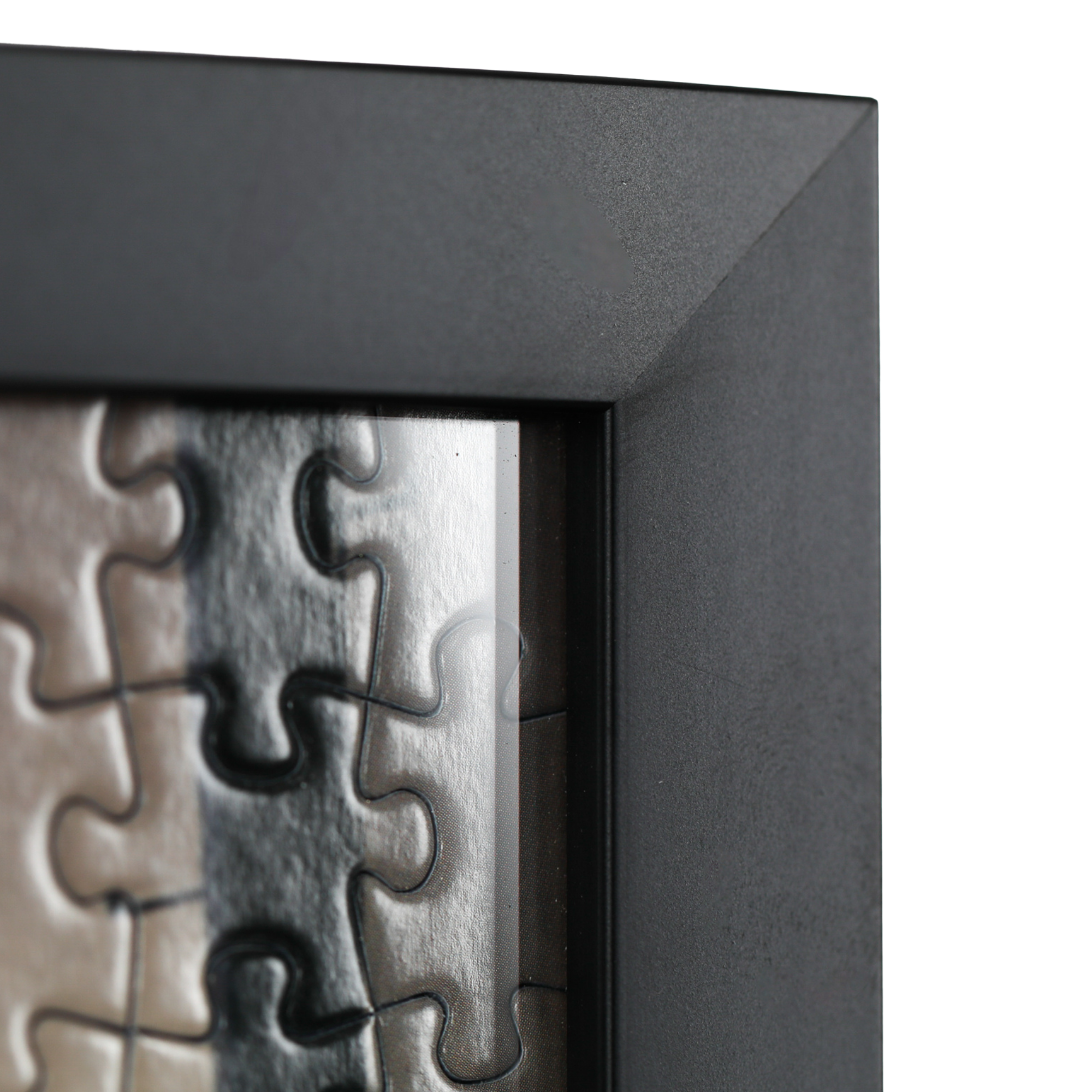 Close-up of custom jigsaw puzzle framing with textured black moulding and precision corner detail.