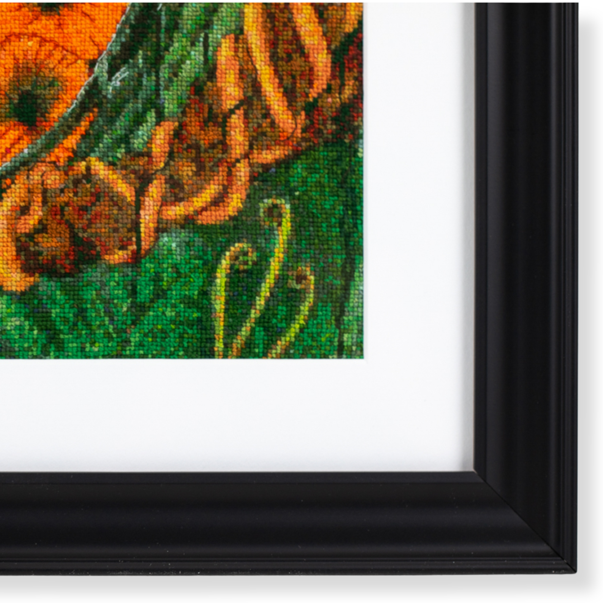Close-up of framed cross stitch artwork showcasing stitch detail and contemporary black framing.