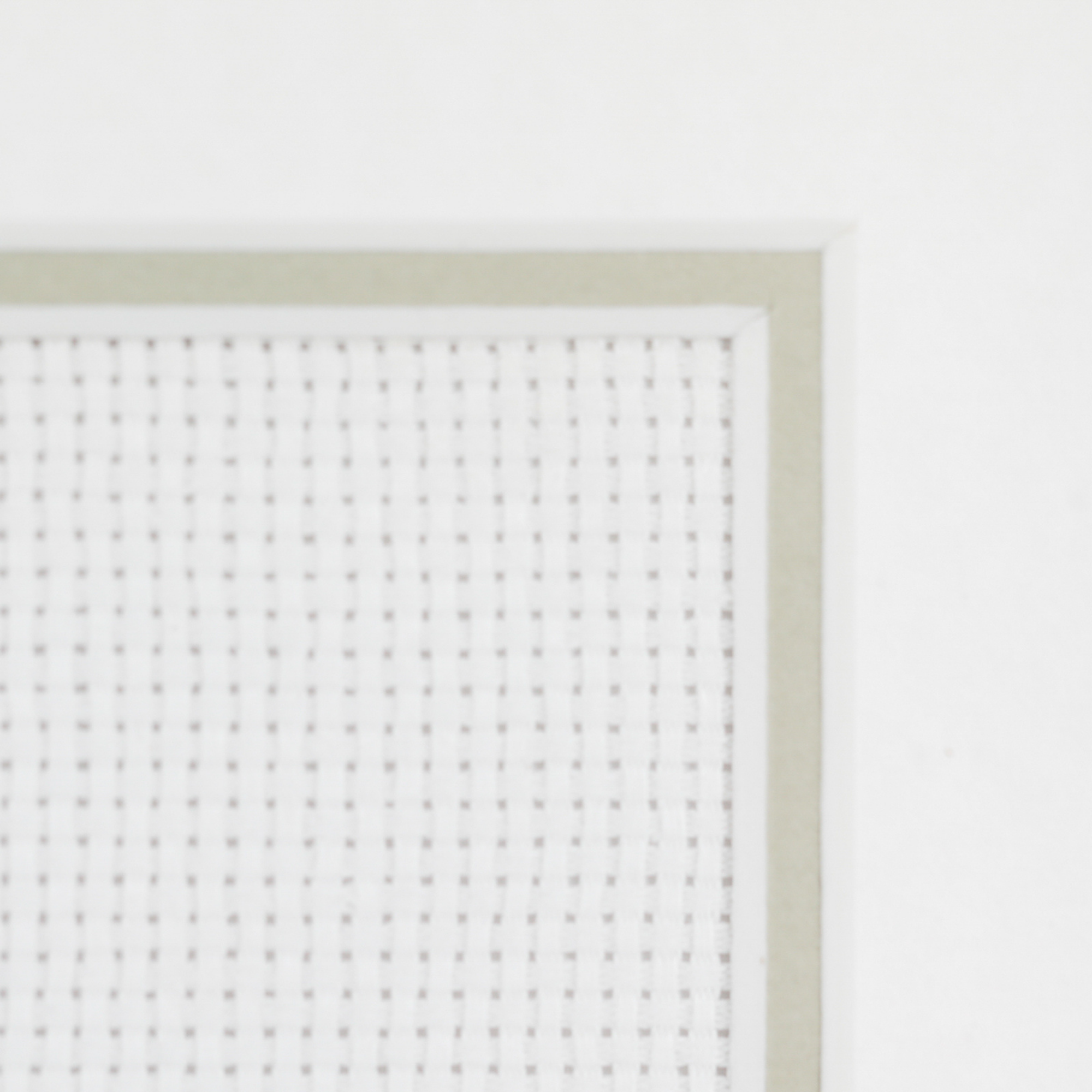 Close-up of custom cross stitch artwork framing showcasing clean fabric mounting and precision textile framing detail.