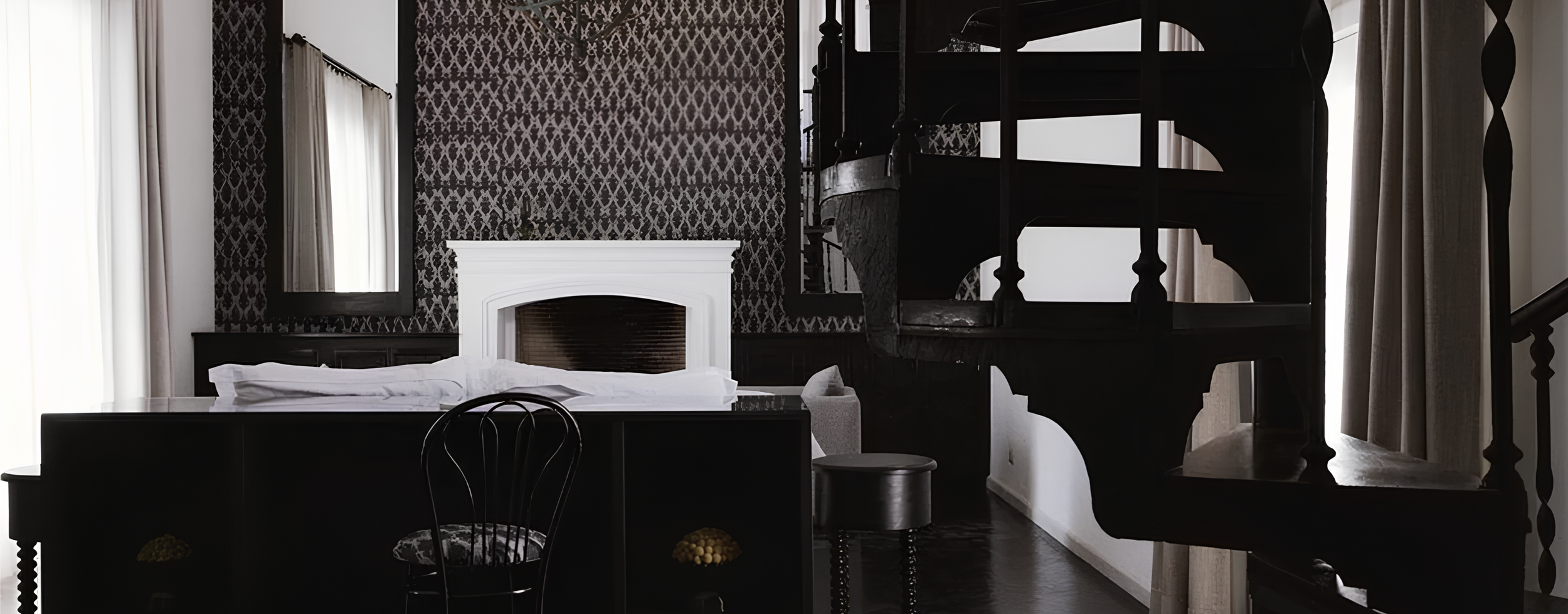 Interior of a bedroom with dark wood furniture, a white fireplace, patterned wallpaper, and a spiral staircase.