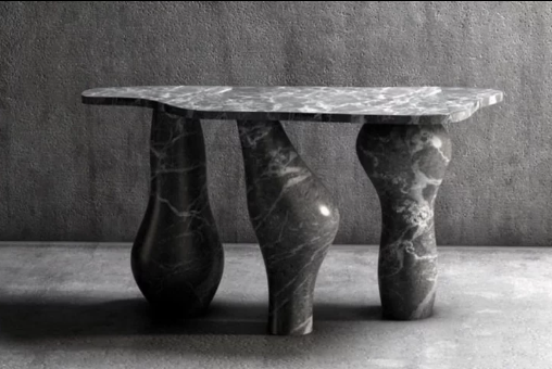 Marble table with uniquely shaped legs against a concrete wall