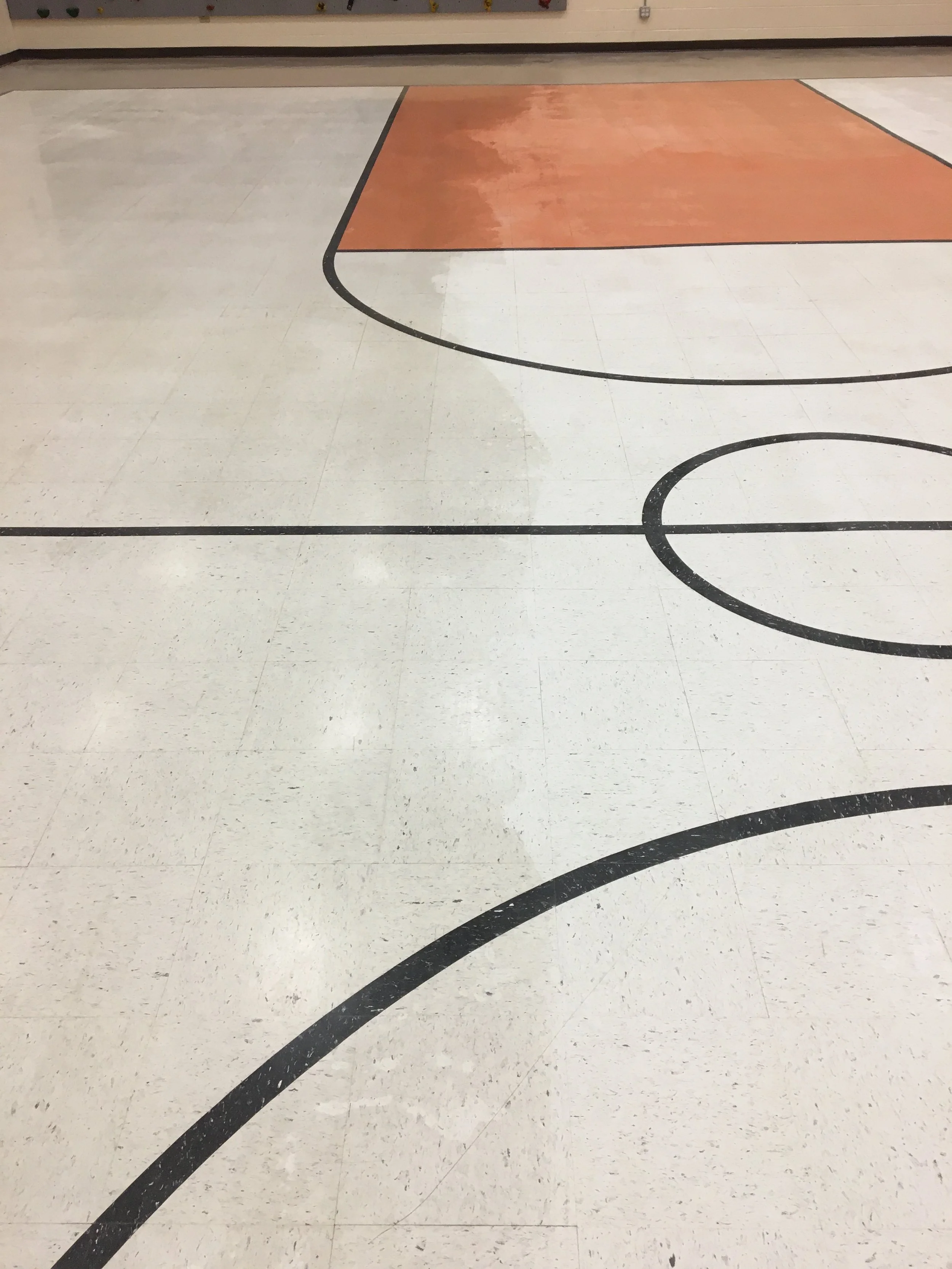 A section of a basketball court with black lines and a painted key area in orange.