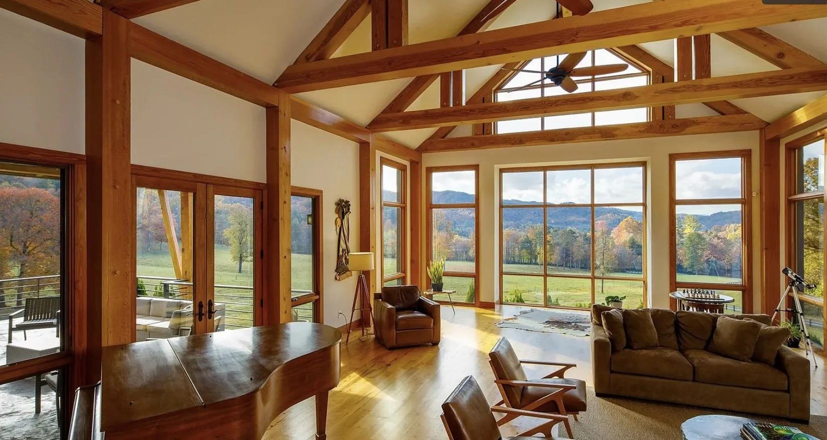 Custom mountain home great room with exposed timber, floor-to-ceiling glass, and mountain views — the kind of high-value Montana property Big Sky Fire Defense designs wildfire defense systems to protect