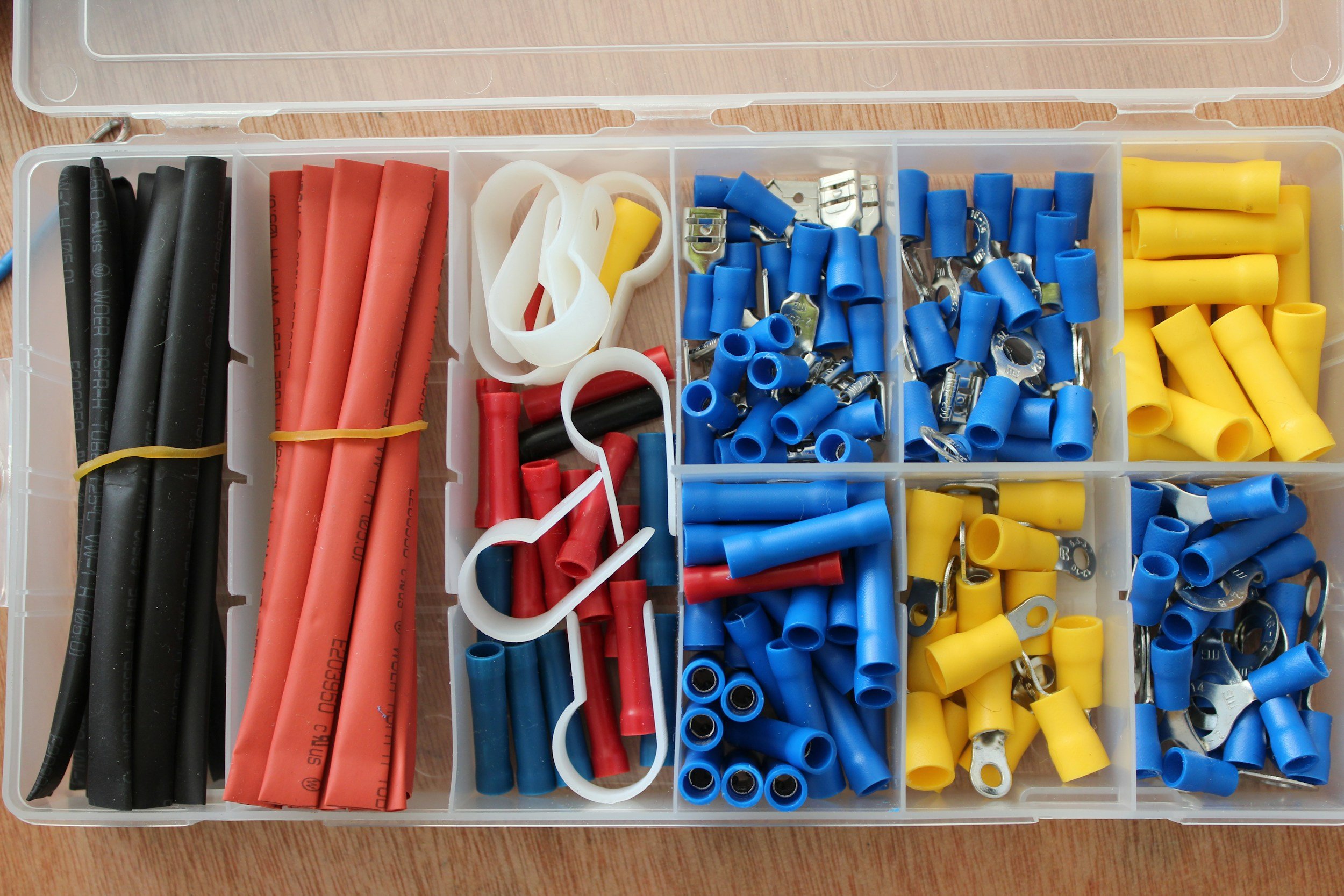 A plastic organizer box filled with insulated electrical wire connectors, including blue, yellow, red, black, and white wire ferrules and terminals.